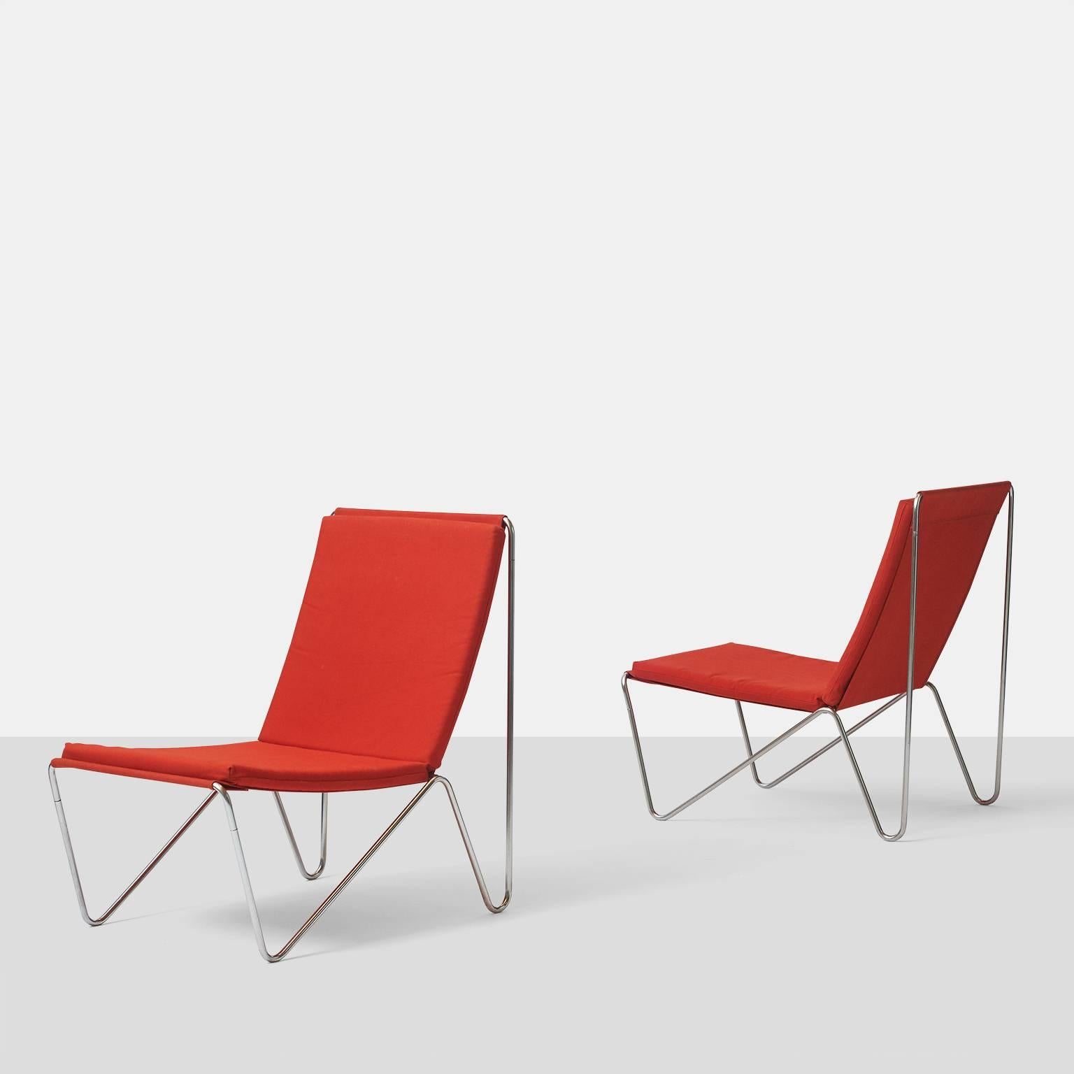 A pair of Bachelor chairs designed by Verner Panton in 1955 and produced by Fritz Hansen. The frame is made of tubular steel and mounted with red canvas and loose seat and back cushions.