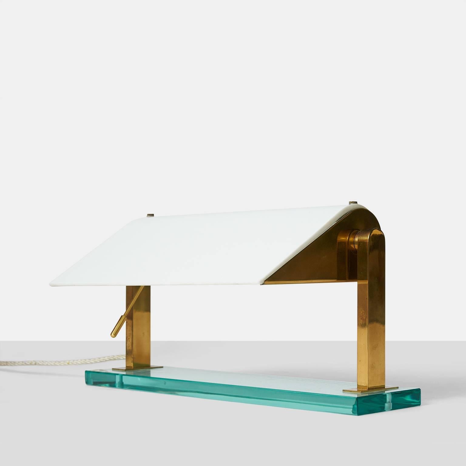 A Classic and contemporary shaped 1940s table lamp by Pietro Chiesa for Fontana Arte. Made with the typical Fontana Arte green glass base, a brass frame, and curved white glass diffuser. The shade's angle can be adjusted by using the brass arm.