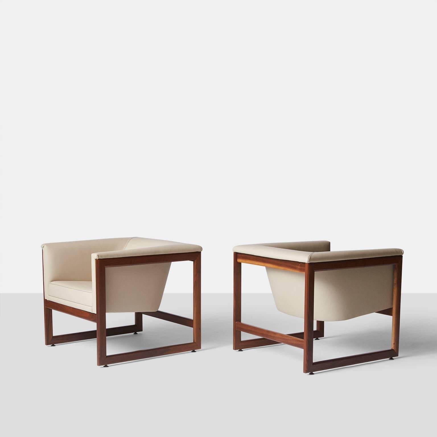 A pair of floating cube chairs by Milo Baughman upholstered in a luxurious ivory leather over a walnut frame.