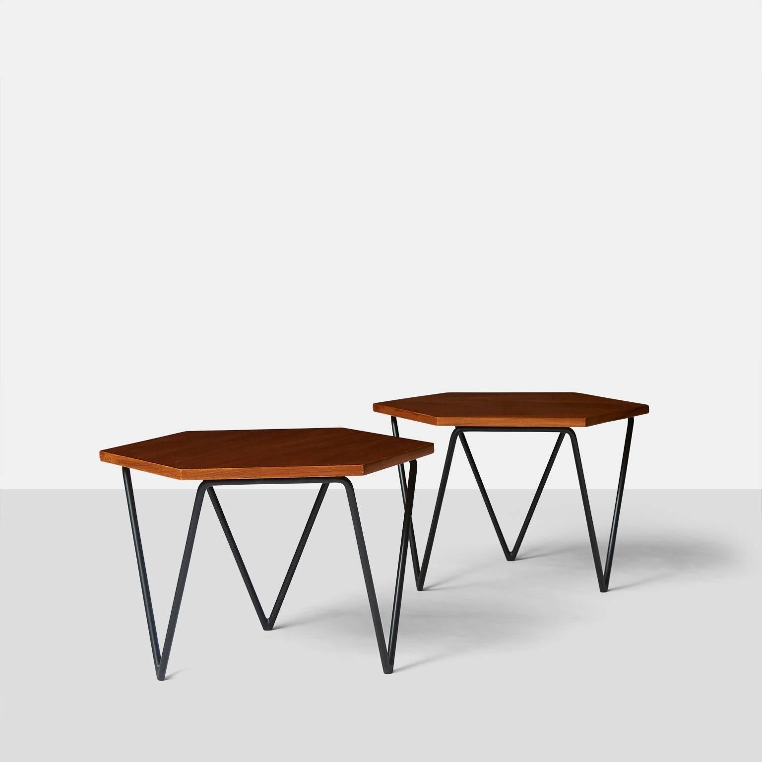 A pair of coffee tables with hexagon shaped tops and three triangular shaped black iron legs. The table tops are made of ash veneer and each retains the original metal label 