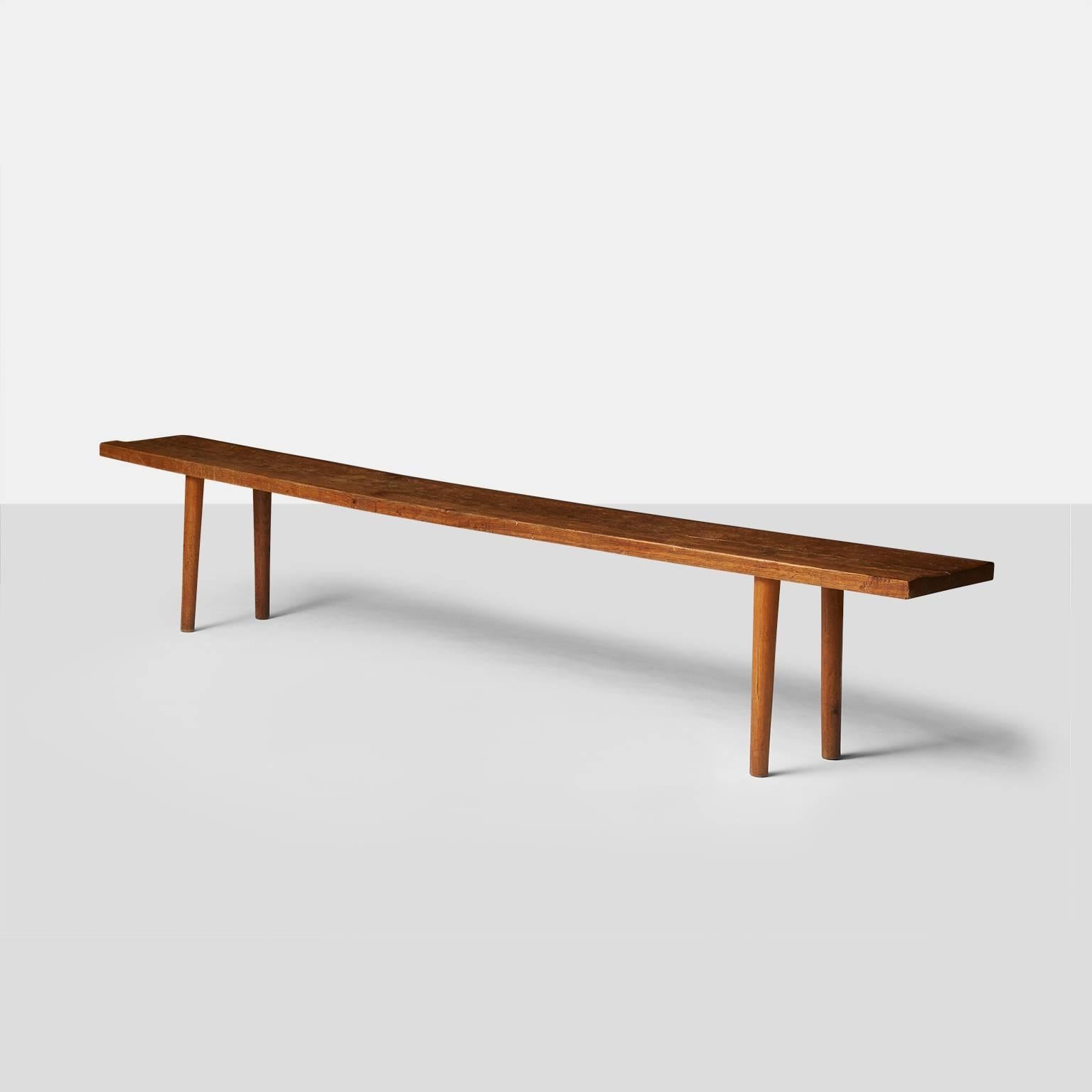 A unique oak bench made in 1955 with a carved texture typical of Jean Touret's work. The seat is made of one solid oak plank and rests on four slightly tapered legs. Retains the original branding 