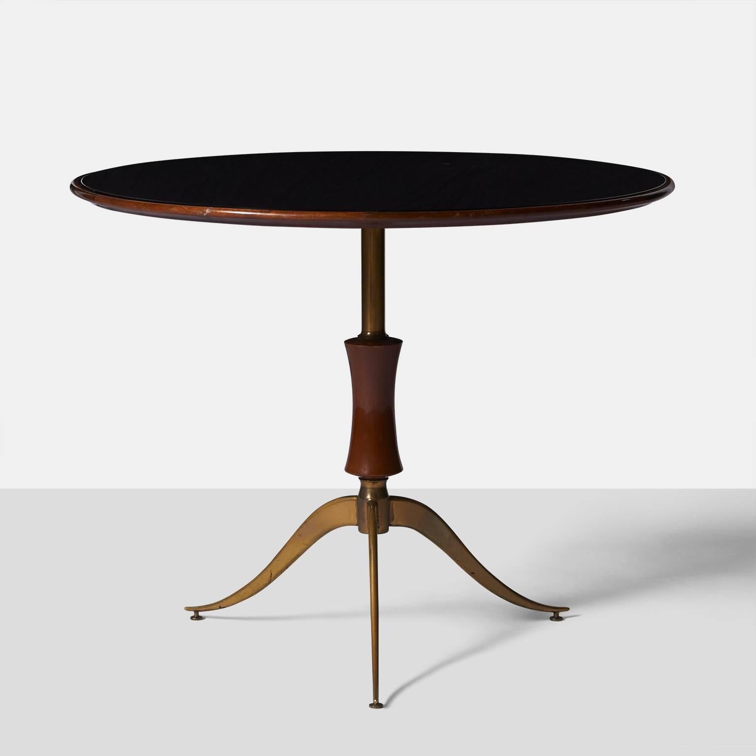 A side table with three slender brass legs, a baluster shaped base and an inset black glass top for Techno, Italy, circa 1956. The top and baluster shaped base are in walnut. Retains the original manufacturers label.