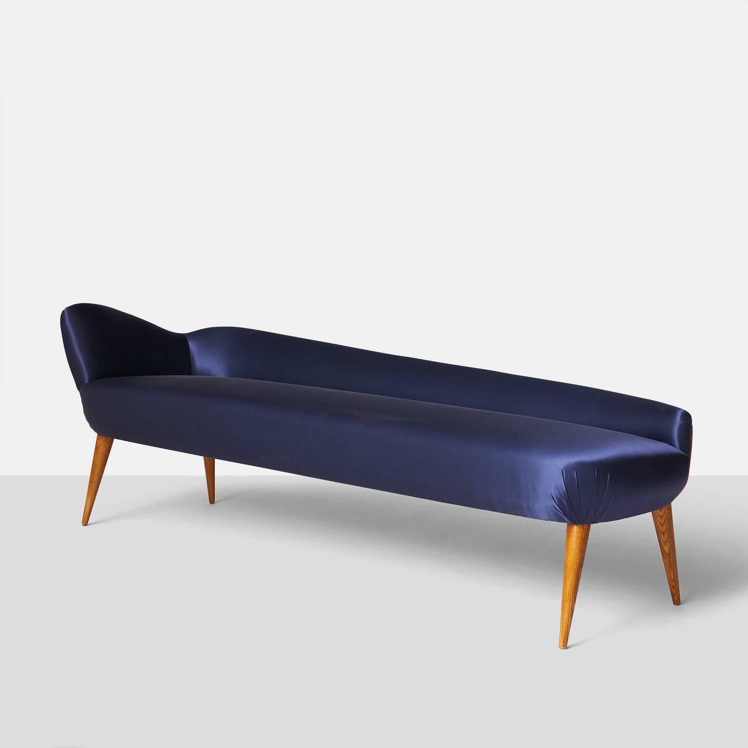 A classic Italian style daybed with oak legs and a sloping back made in the style of Ico Parisi. Upholstered in a deep blue satin fabric, Italy, circa 1950.