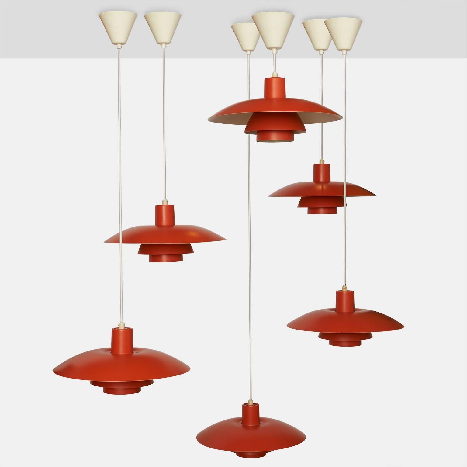 A group of eight orange lacquered metal pendants by Poul Henningsen for Louis Poulsen, Denmark. Each pendant has 8' of cord. Priced individually.