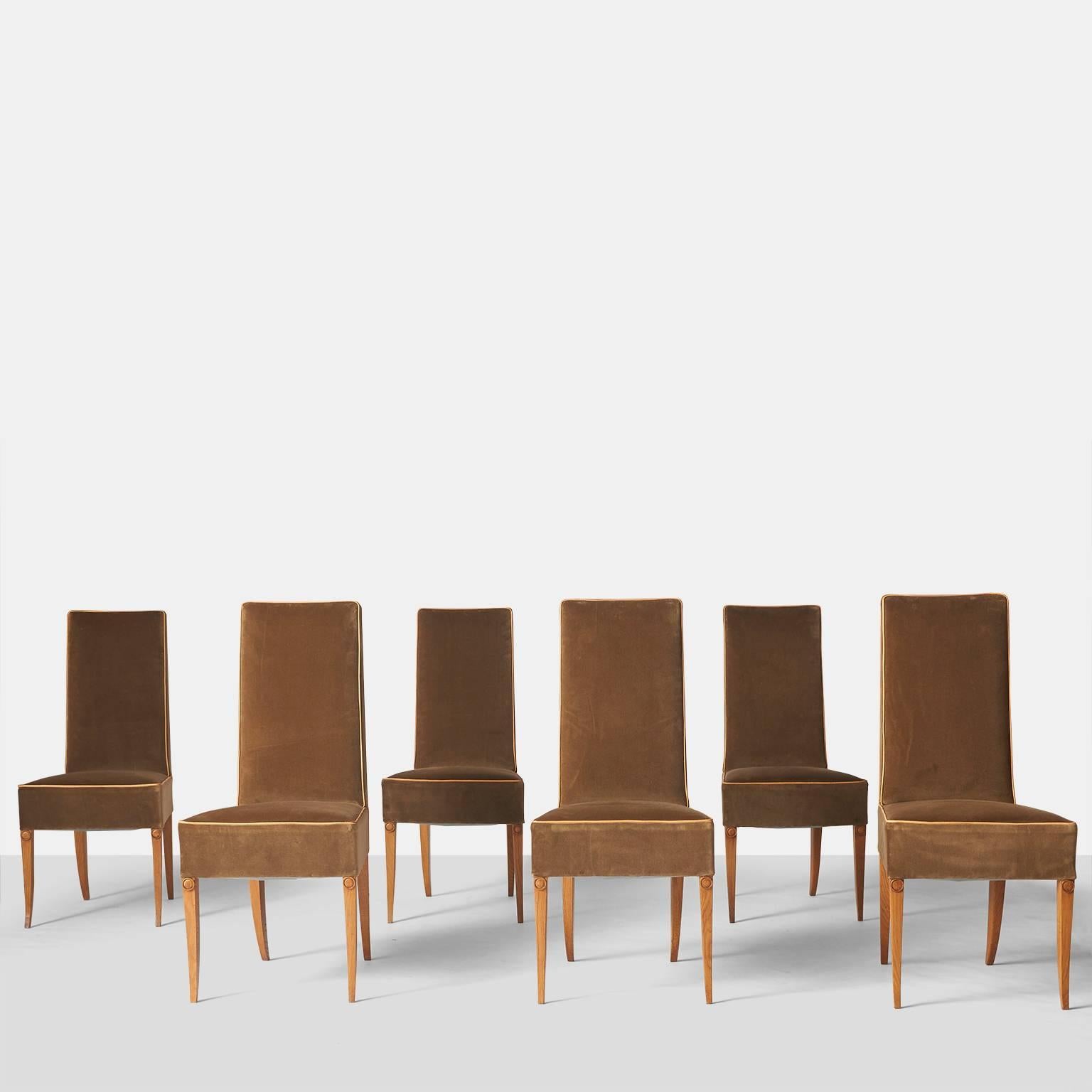 A set of six dining side chairs in limed oak by Andre Arbus upholstered in a brown velvet fabric with contrasting leather trim. The oak frame legs have the Classic flare on the bottom with a circular rosette on top of each leg. Made in France, circa