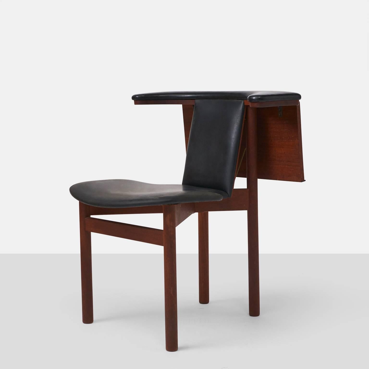 A side chair with black leather seat and back with a drop leaf style adjustable shelf on the back for reading or eating. Designed in 1964 by Hans Olsen. Teak frame.