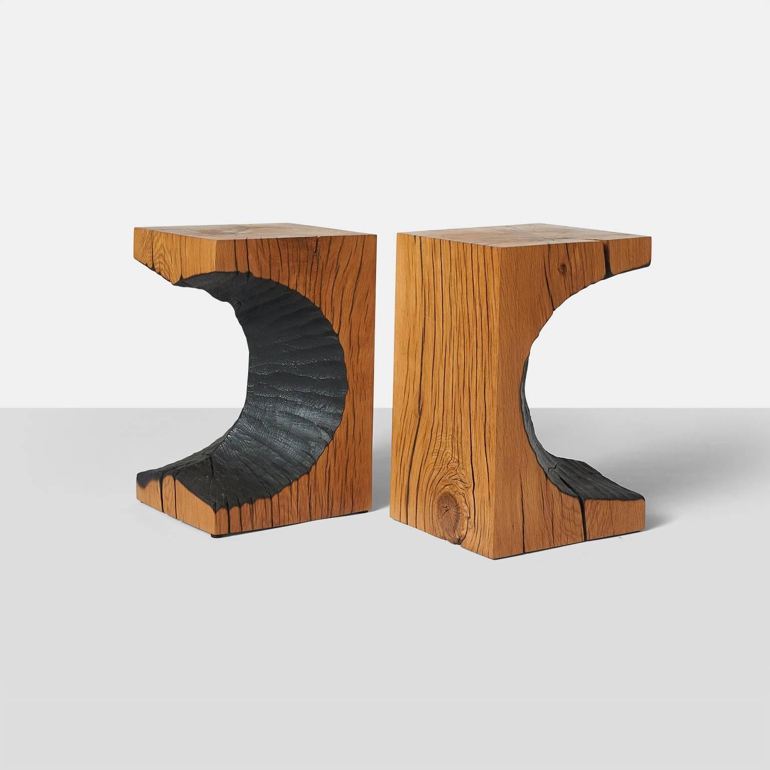 A pair of oak side or coffee  tables made by German artist Kaspar Hamacher from a solid piece of oak.  The center of the trunk has been carved out to create a circular pattern and the finish is blackened.  The oak is from naturally fallen trees,