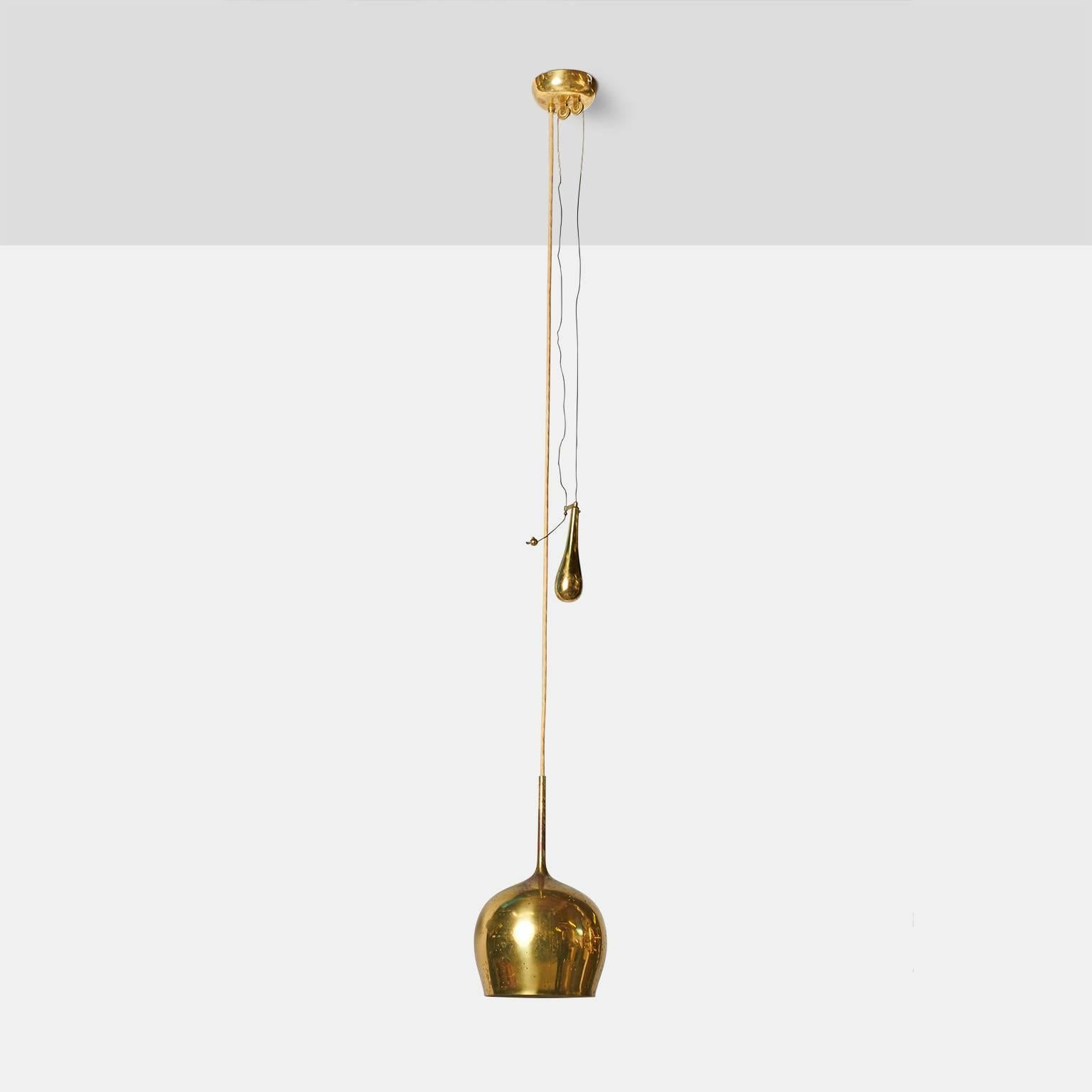 A counter weight pulley pendant by Paavo Tynell for Taito Oy with perforated brass shade and brass weight. Overall length can be adjusted.