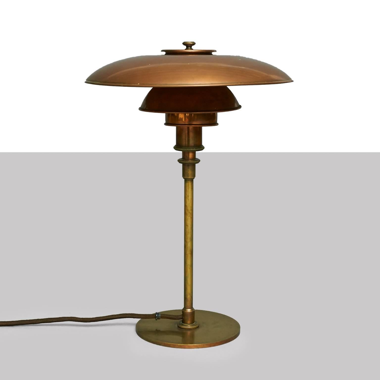 A table lamp by Poul Henningsen with browned brass frame, socket cover and top, mounted with 3/2 patinated copper shade set. No switch on the frame. Stamped 'Pat. Appl.' (highly valued to PH collectors). Early model produced by Louis Poulsen in