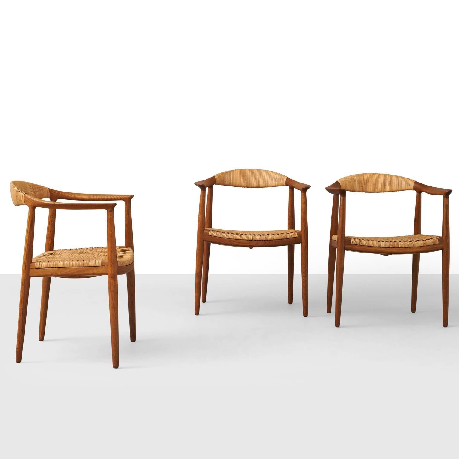 Earliest version of 'The Chair.' Open-arm chairs of oak with caned seats. Curved back and tapering legs. Made by Johannes Hansen. Branded, Johannes Hansen Copenhagen, Denmark. Priced individually.