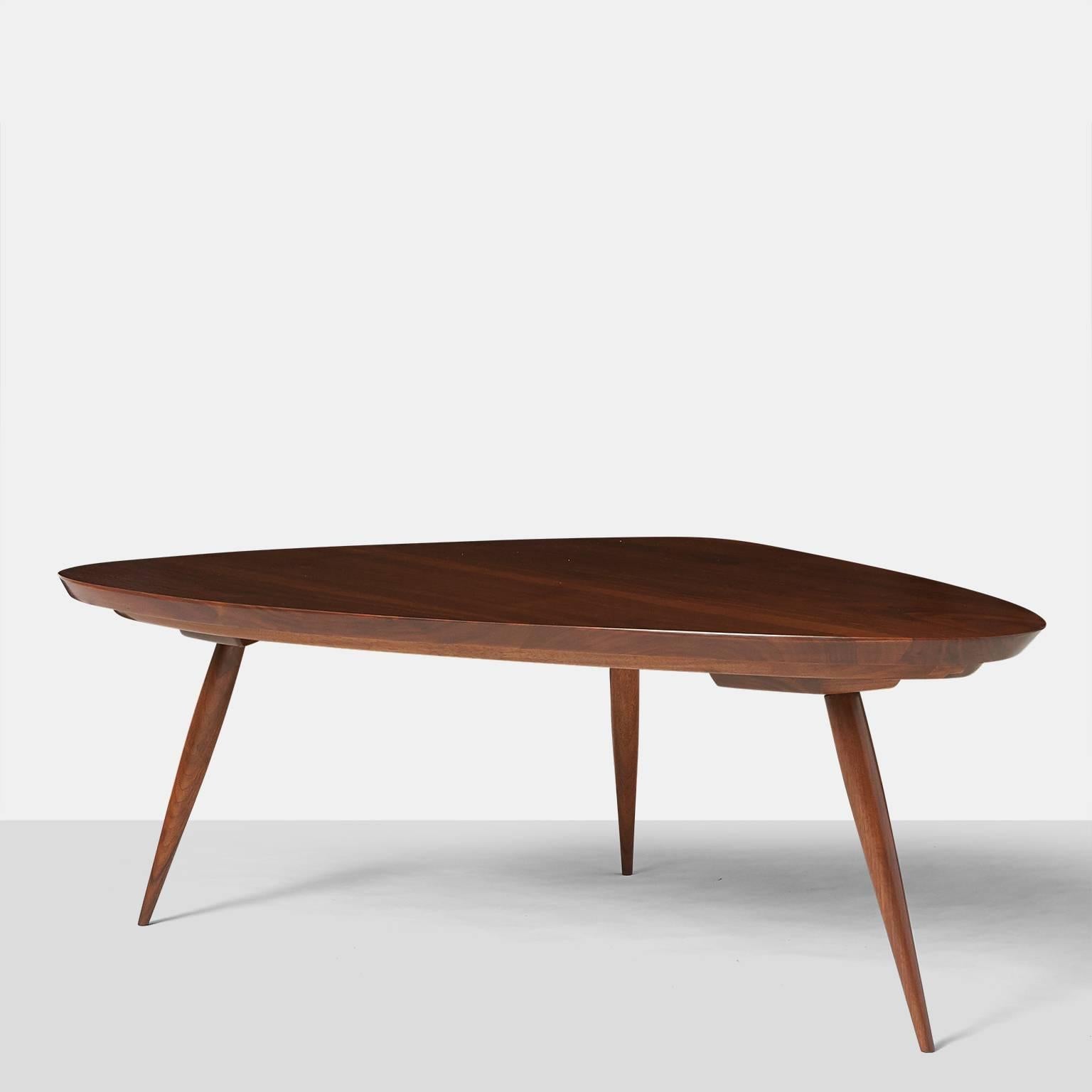 An extra large triangular shaped coffee table with rounded corners in black walnut on tapered legs. A pair of smaller version tables are available,
USA, circa 1960s.