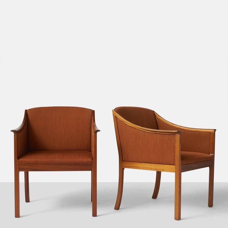 A pair of lounge chairs with mahogany frame and upholstered in a deep terracotta wool fabric. Designed by Ole Wanscher in the 1950s and manufactured by Poul Jeppesen.