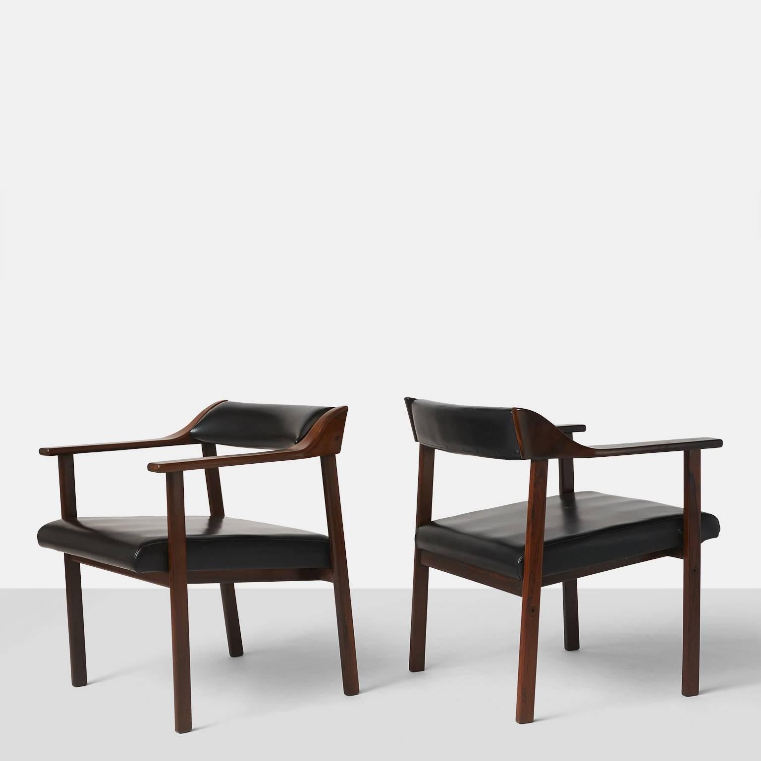 A pair of chairs in Jacaranda and upholstered in black faux leather, made in Brazil, circa 1950 by Joaquim Tenreiro. A total of four chairs are available.