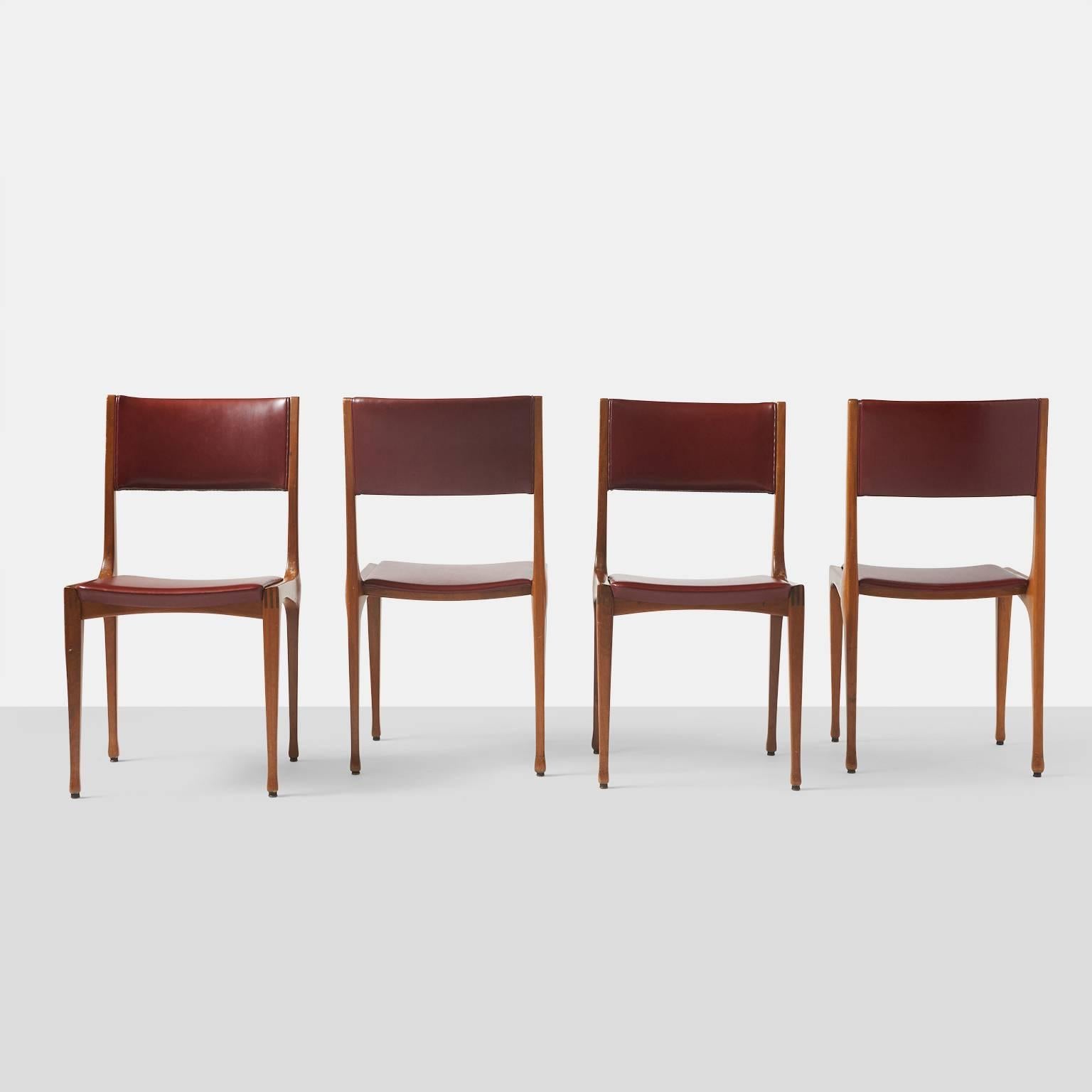 A set of four dining side chairs model #693 in walnut with burgundy leather upholstery for Cassina.
Italy, circa 1950s.
 
