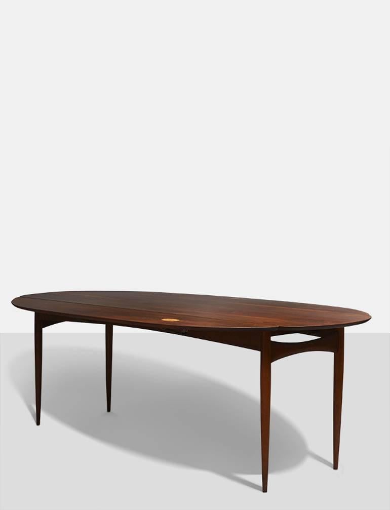 An extremely rare dining table by Phillip Lloyd Powell. Walnut with drop-leaf sides that feature inlays of stone.