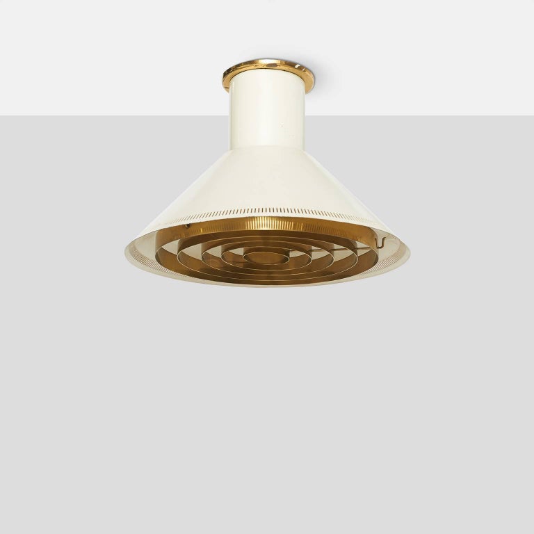A round flush mounted ceiling fixture in white enameled steel with brass diffuser and a perforated outer edge on frame. The cap at ceiling is stamped Taito.
Finland, circa 1950s.