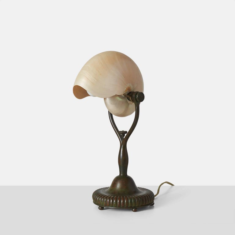 A nautilus table lamp by Tiffany Studios in bronze with wishbone shaped base. A metal Loop on base allows this to be wall hung as well. 
Stamped on the base Tiffany Studios New York 266.


 