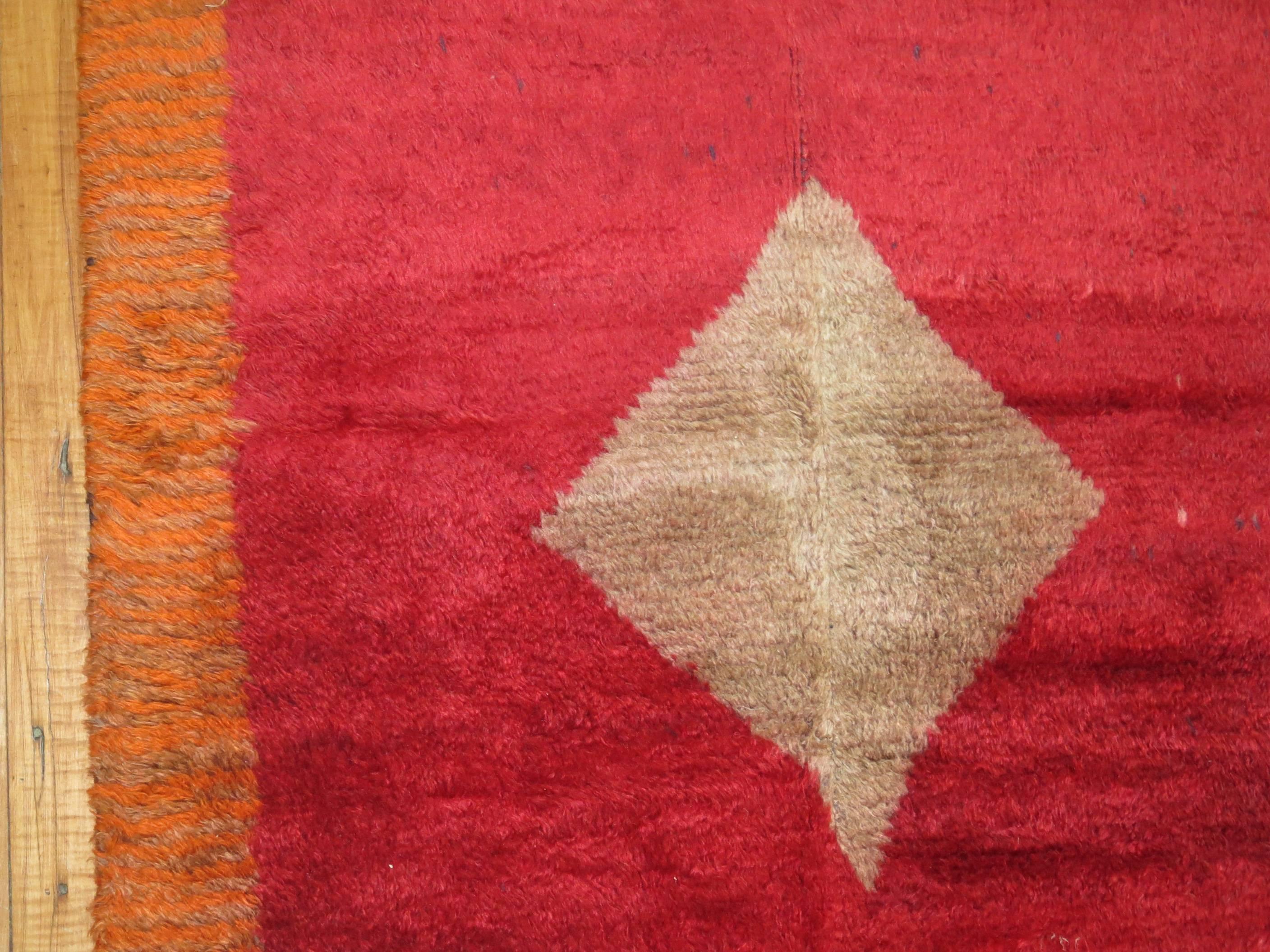 Turkish Tulu Bedding rug with an off center gray medallion set on a plain cherry red field and pumpkin orange border. 
Measures: 3'3” x 5'5”.