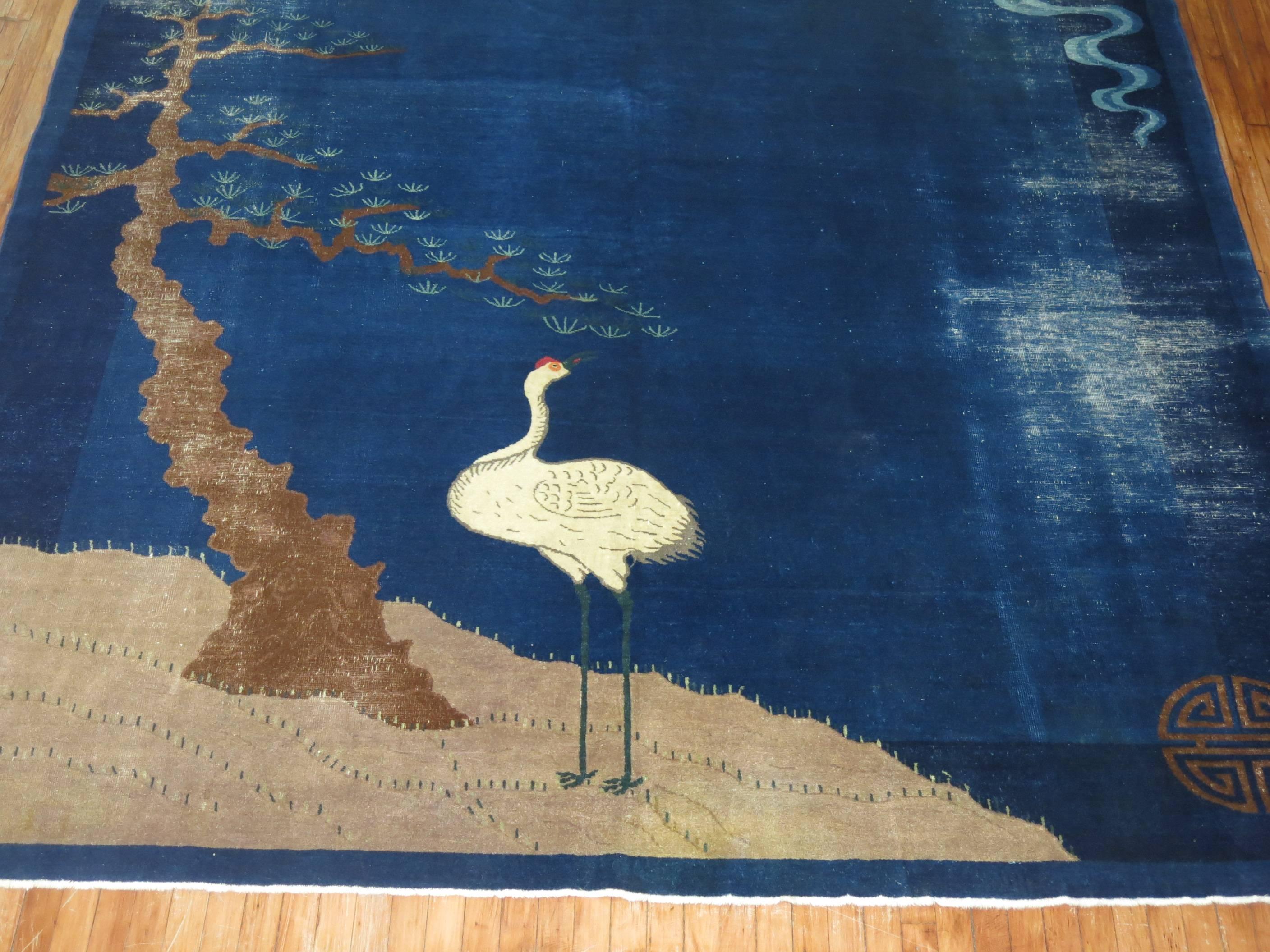 A pictographic Nichols Chinese Art Deco rug with a pigeon, bird and bonzai tree on a navy blue field.