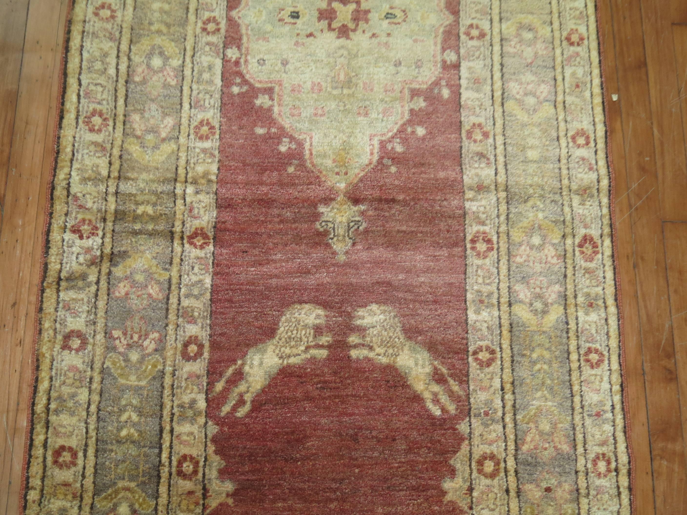 A decorative subtle colored Turkish runner depicting four lions in between a central medallion motif and multiple borders. A small goat is on a circular pattern was woven in by this extremely creative Turkish weaver. Accents in soft red, brown, gray