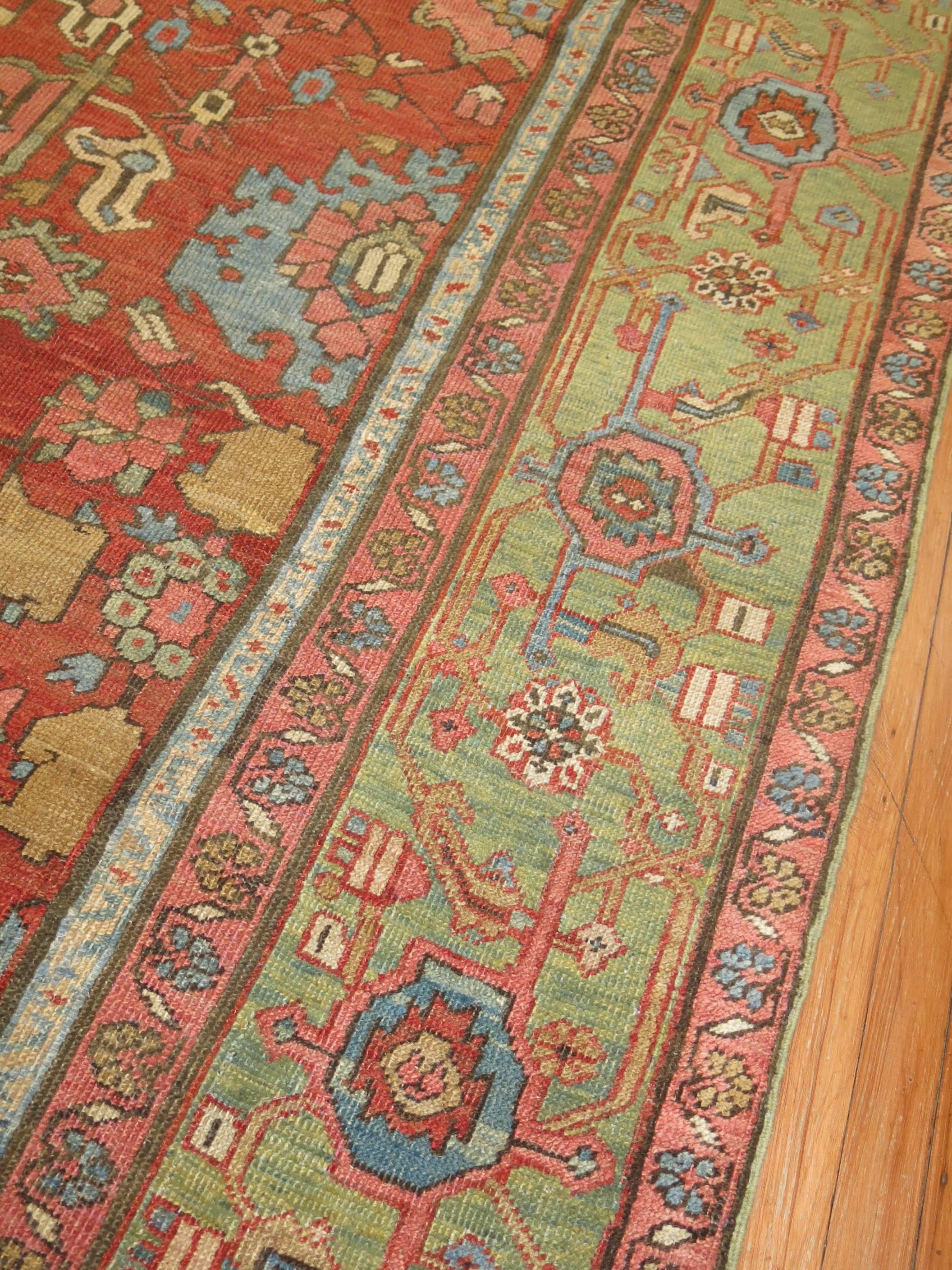 Colorful all-over design, early 20th century room size Heriz carpet. Orange-red field, light green border, accents of blue, terracotta, pink and camel.