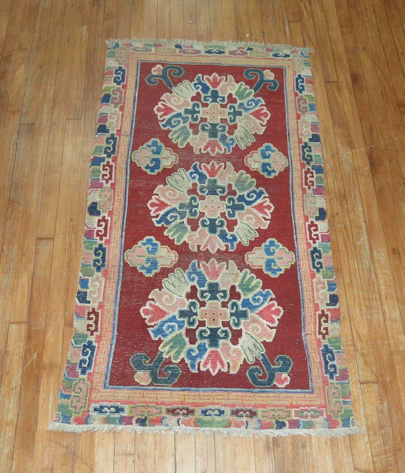 An exquisite antique Tibetan rug. Chinese red field with other colorful accents.