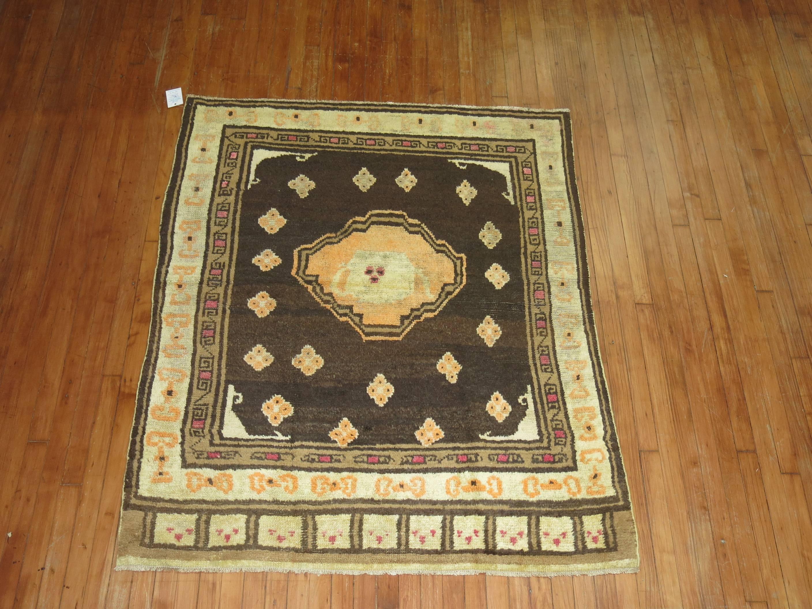 Tapis excentrique de l'est du Turkménistan avec un médaillon en forme de thé, des accents en canteloup et ivoire sur un fond brun. Le tisserand a intentionnellement laissé de côté une bordure d'extrémité pour lui donner un aspect plus désirable.