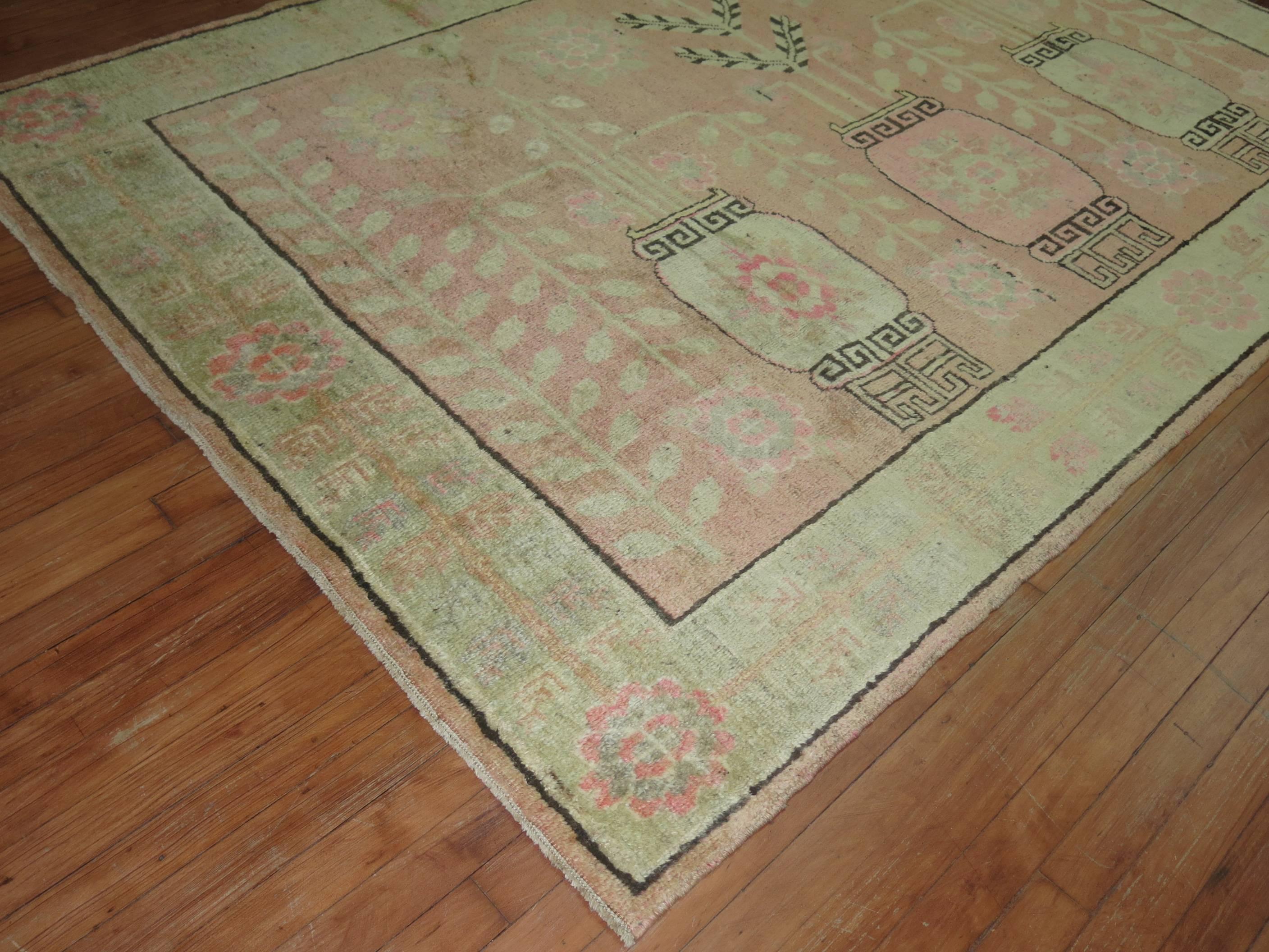 One of a kind Khotan rug with a soft pink field consisting of a flower vase motif and a soft green border.