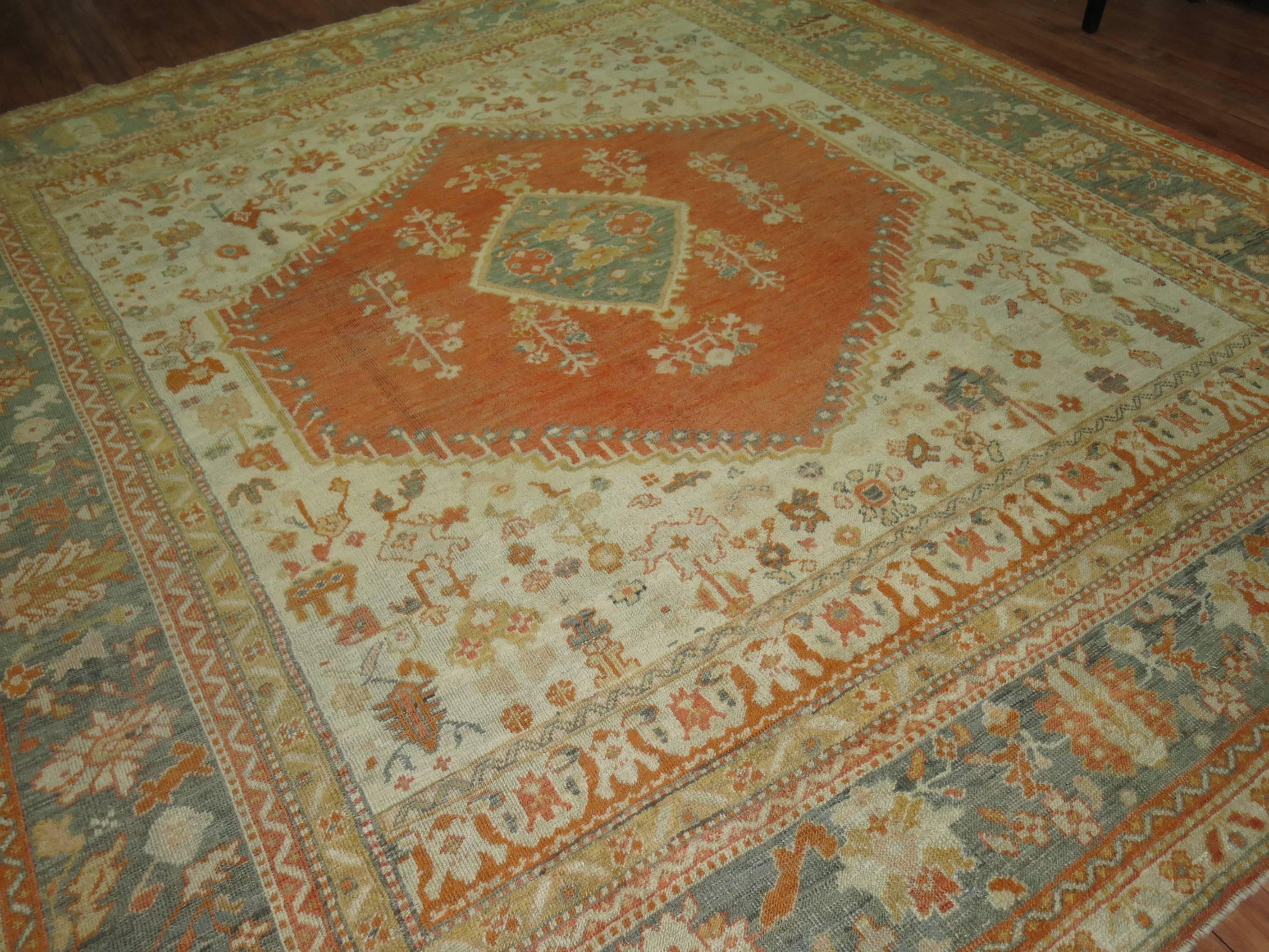 Stunning early 20th century antique Oushak carpet with a medallion covered by an ivory ground and teal border.
