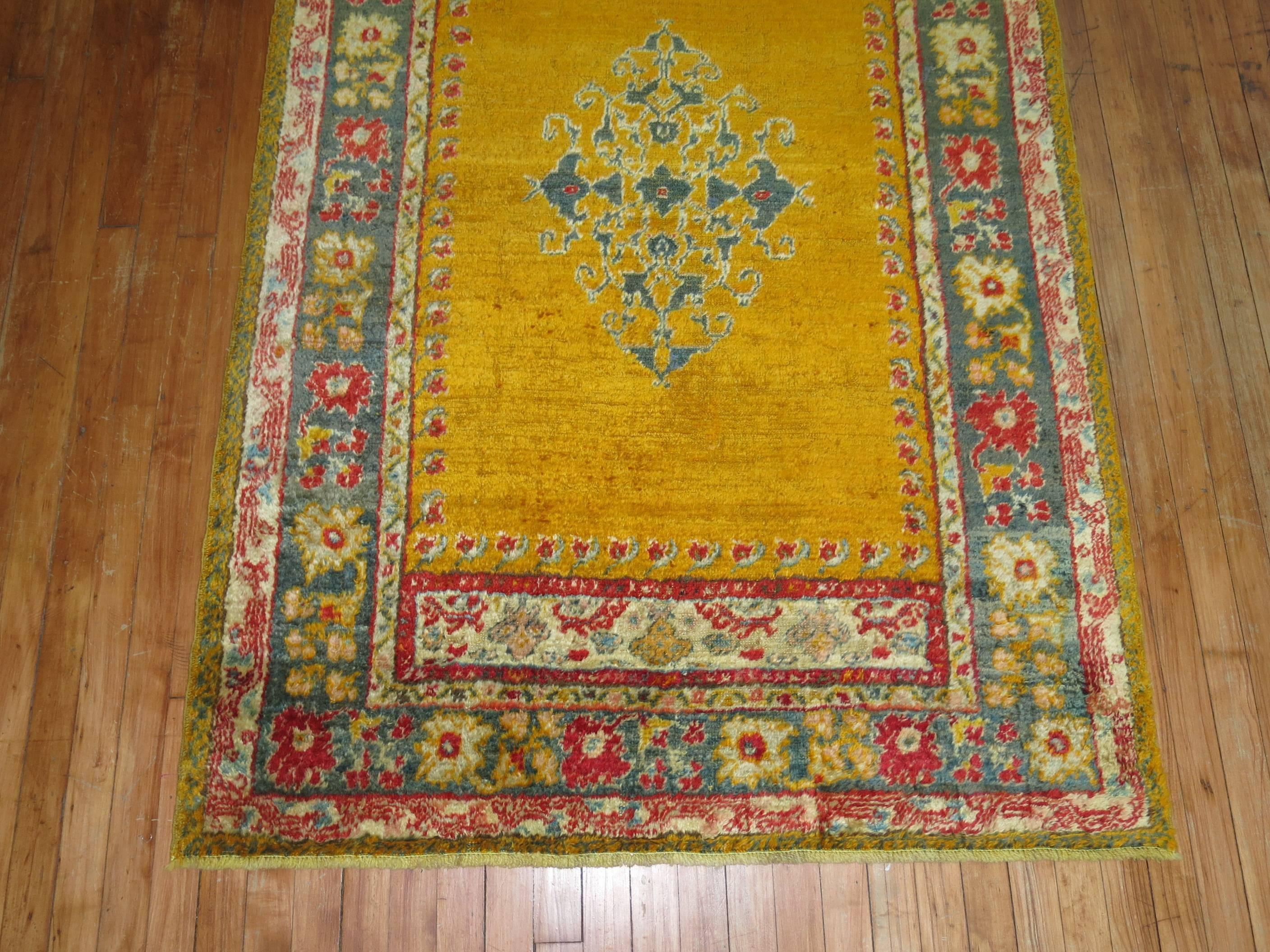 An early 20th century angora wool Oushak rug with a saffron gold colored ground on an open field and center medallion.

4'1'' x 6'3''