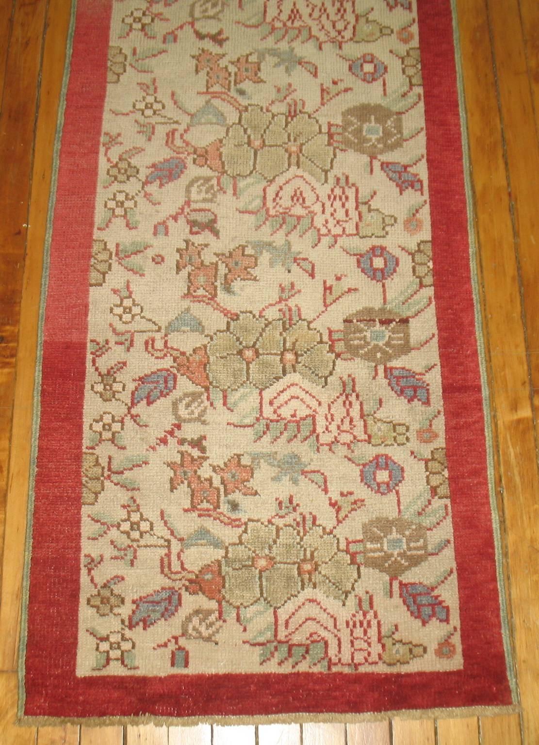 A narrow vintage Turkish runner with a floral design on an ivory ground and solid blood red border.