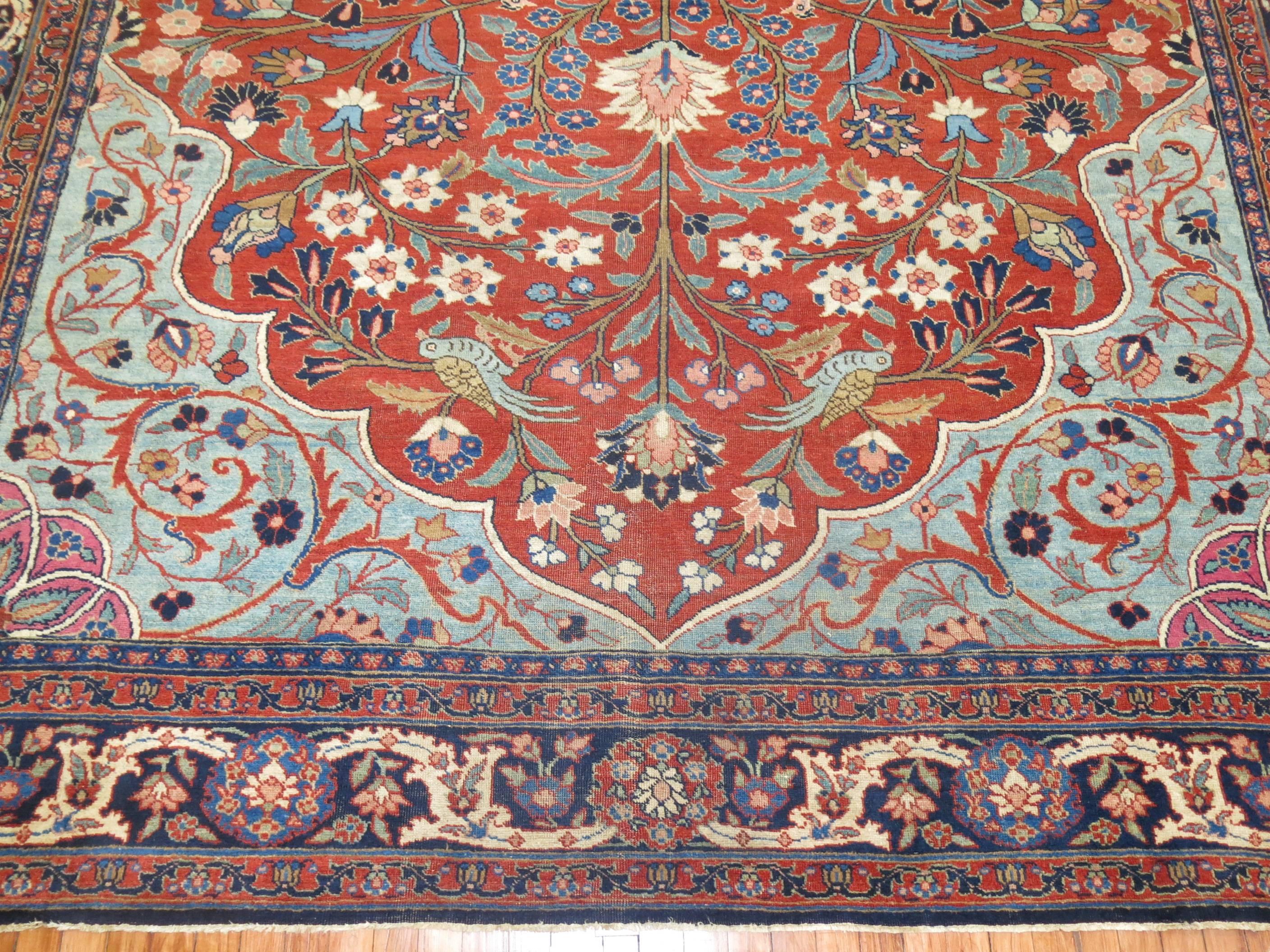 An early 20th century Persian Tabriz pictorial carpet. Orangy red field with navy border and some light blue accents.

Measures: 10' x 12'6''.