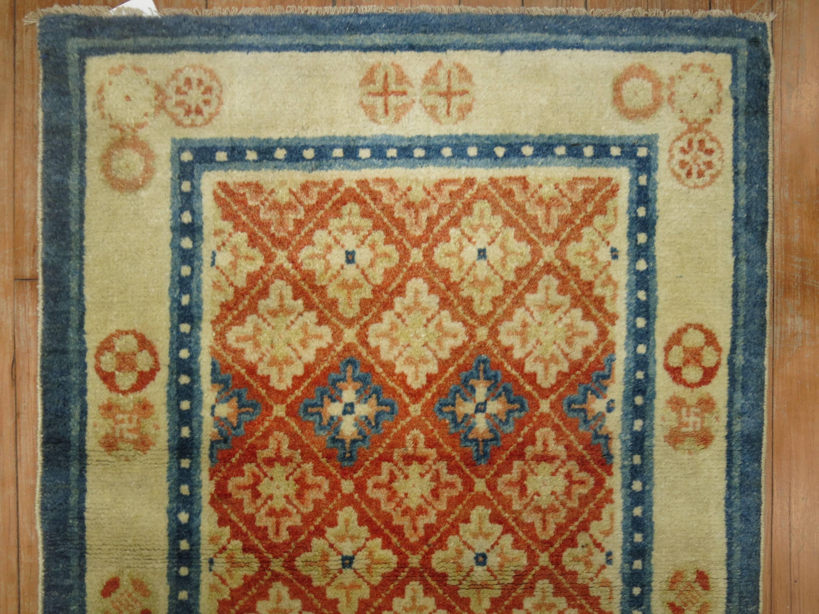 An antique Tibetan throw size wrong with a sweet potato colored ground, accents in tan and blue.