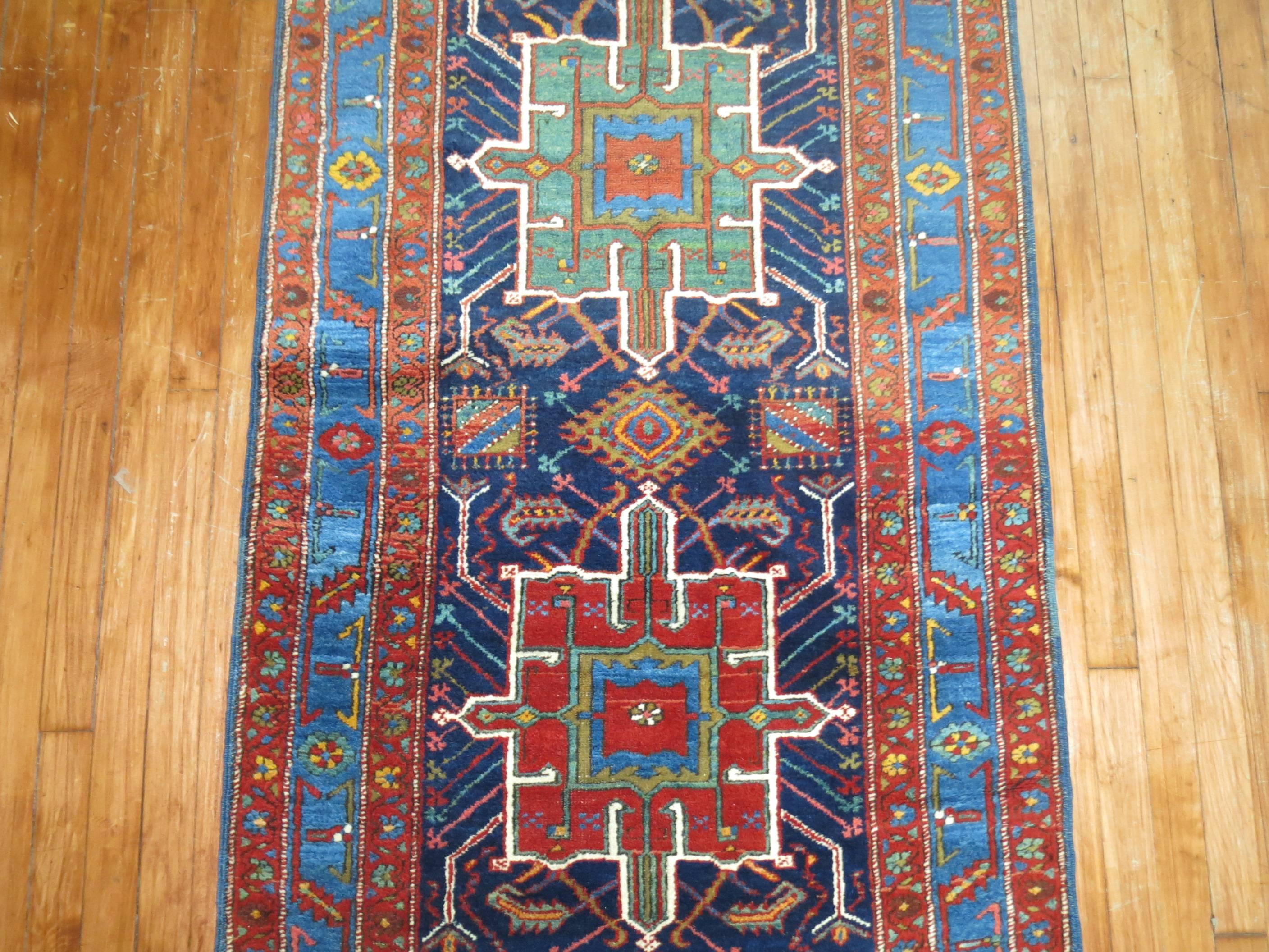 Colorful antique Persian Heriz Karadja runner. Navy background with predominant accents in sky blue and rust.