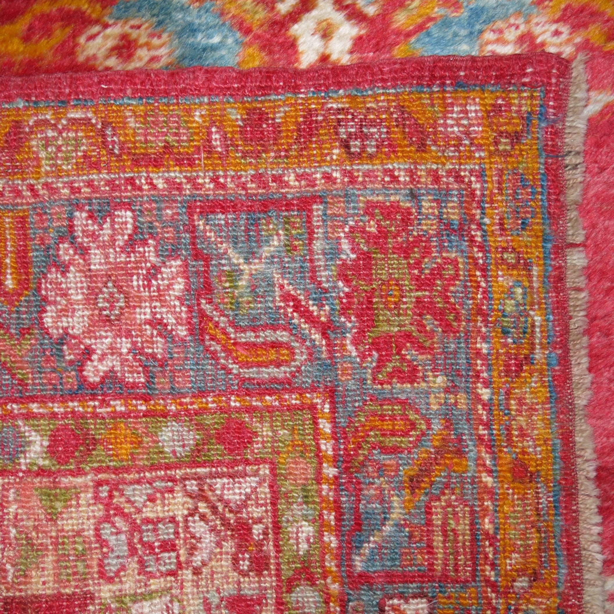 An antique angora wool authentic Oushak rug featuring bright colors from the early 20th century. The field is red, accents in turquoise and orange

Measures: 3'6