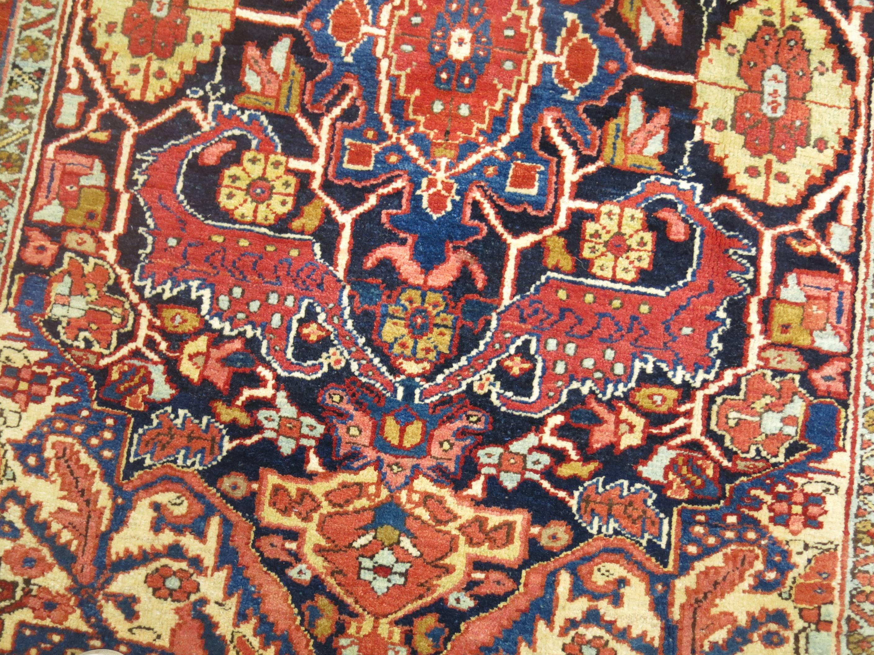 Ein authentischer vollfloriger persischer Heriz-Teppich. Die Palette ist formal, die Umrandung hat einen orangeroten Farbton, während das Feld marineblau ist. 

Maße: 4'7