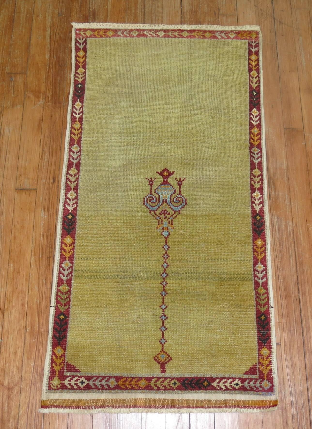 An antique Turkish rug with an irregular formal motif on a pea green colored ground.