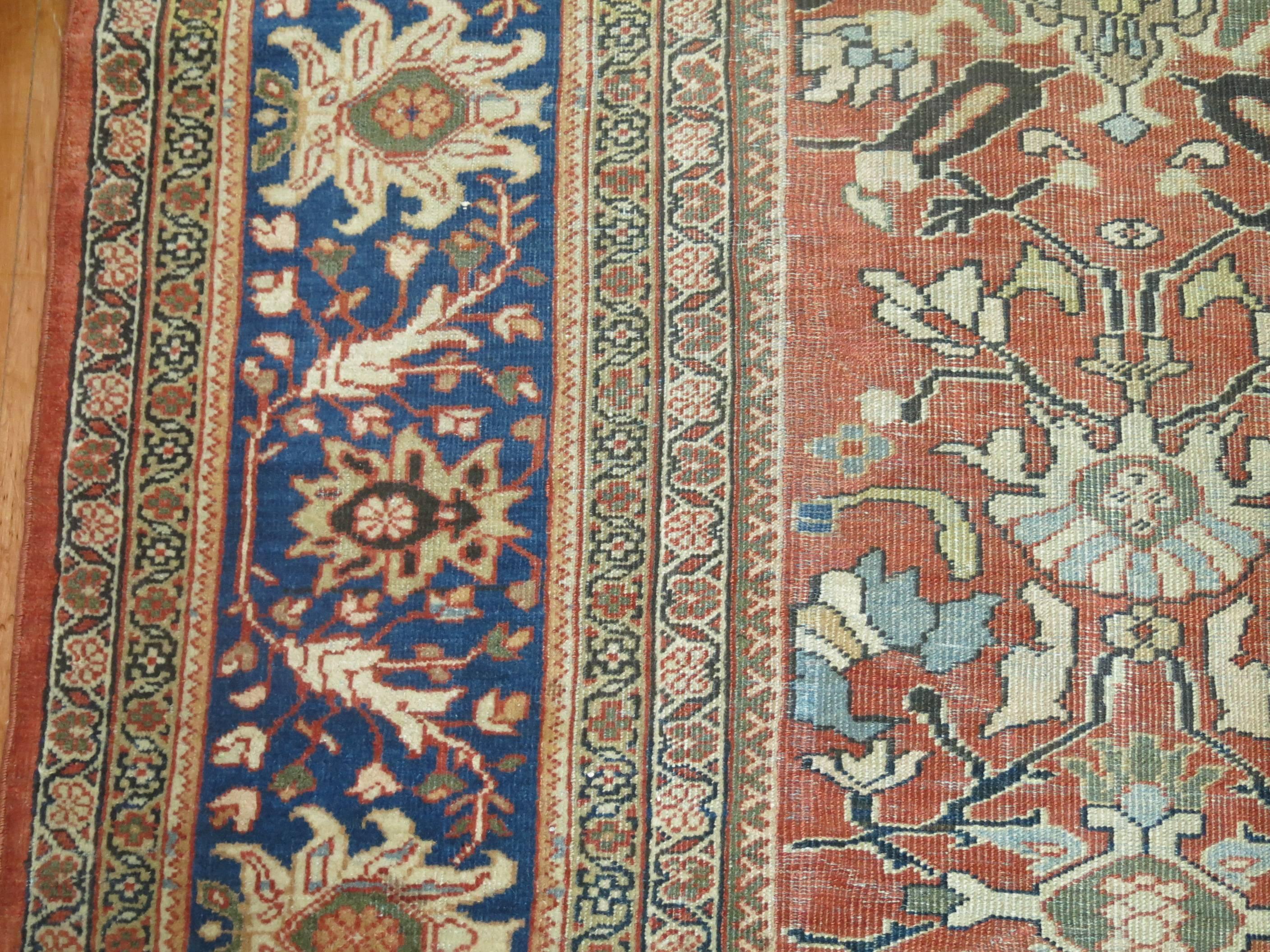 An oversize decorative antique Persian Mahal rug. Soft Terracotta field and blue border.

Measures: 12'7'' x 20'6''.