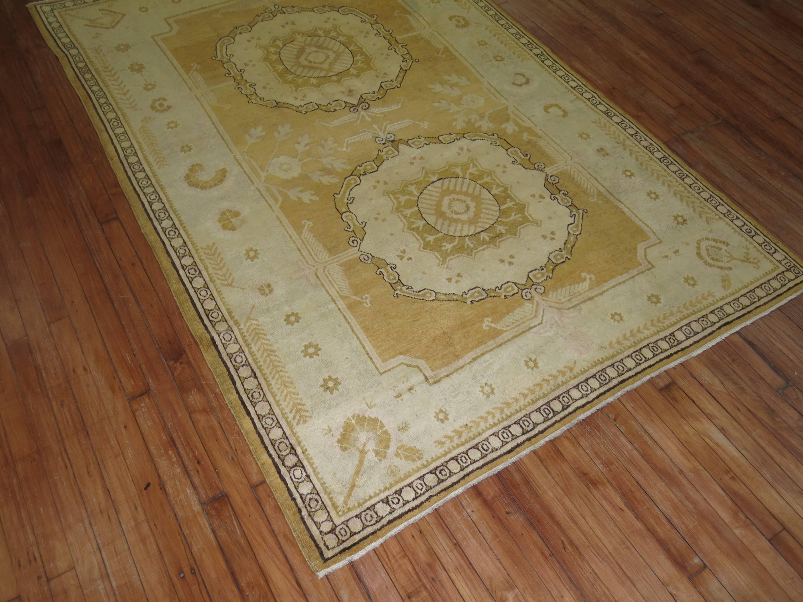An East Turkestan rug in rare yellow shade. Two elegant round medallions surrounded by a charming ivory colored border and yellow ground.