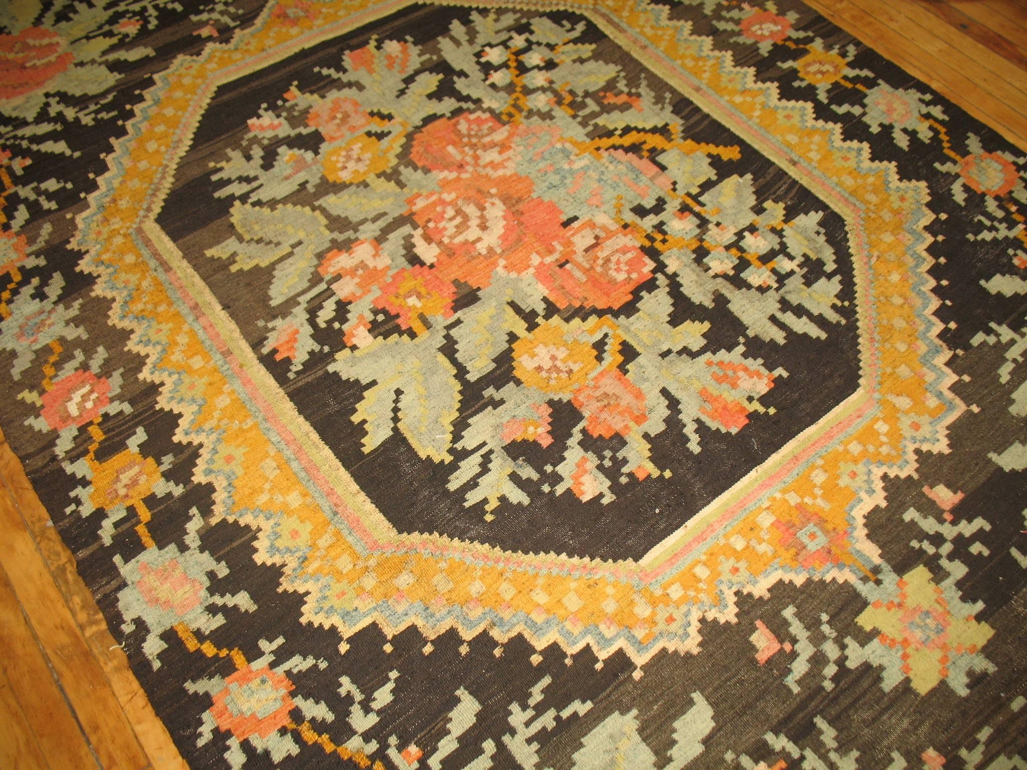 Vintage Besserabian Kilim with a large scale floral motif in bright yellow, light green and orange accents on a brown field

6' x 8'9''