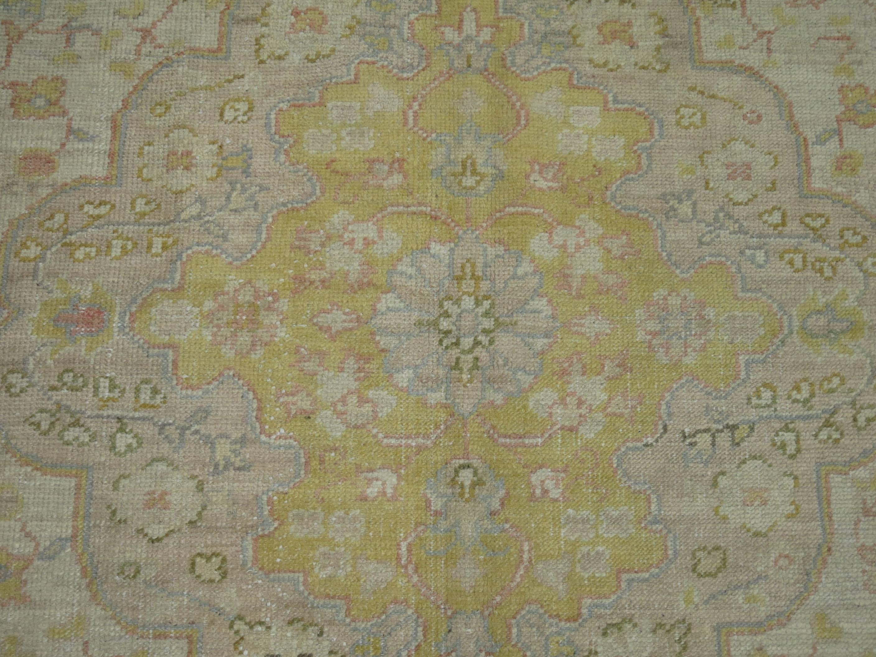 An early 20th century antique Turkish Oushak rug consisting of an ivory ground, predominant accents in yellows and pink.

Measures: 11'2'' x 14'5''

Turkish Oushak rugs have become the one of the top decorative rugs of choice for many of the top