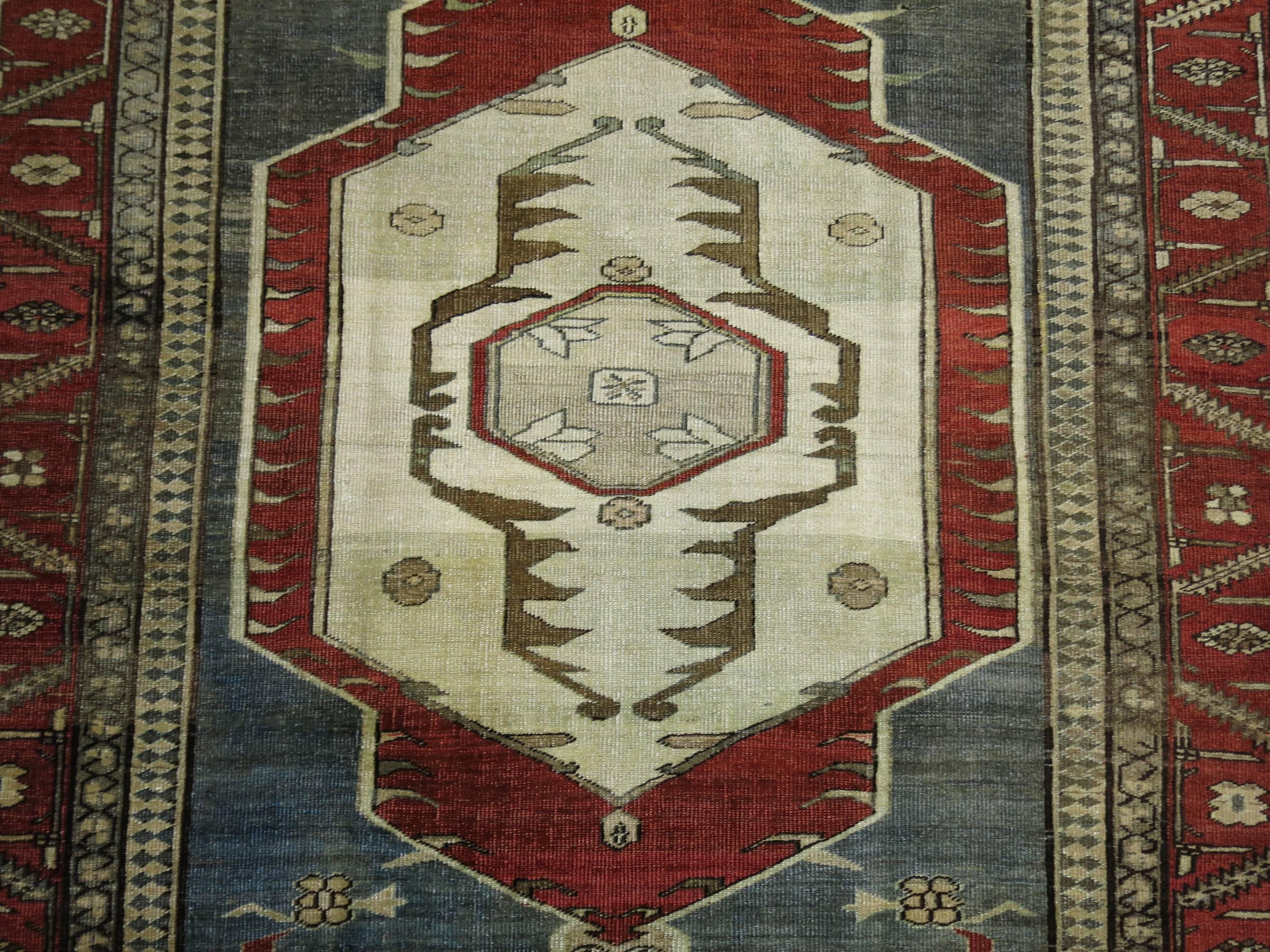 An early 20th century fine quality Persian Serapi rug. Predominantly grey, rust, and brown. On both ends of the central medallion is an interesting half facial figure with eyes.

4'8'' x 6'11''

With distinctive large-scale motifs and a wide ranging