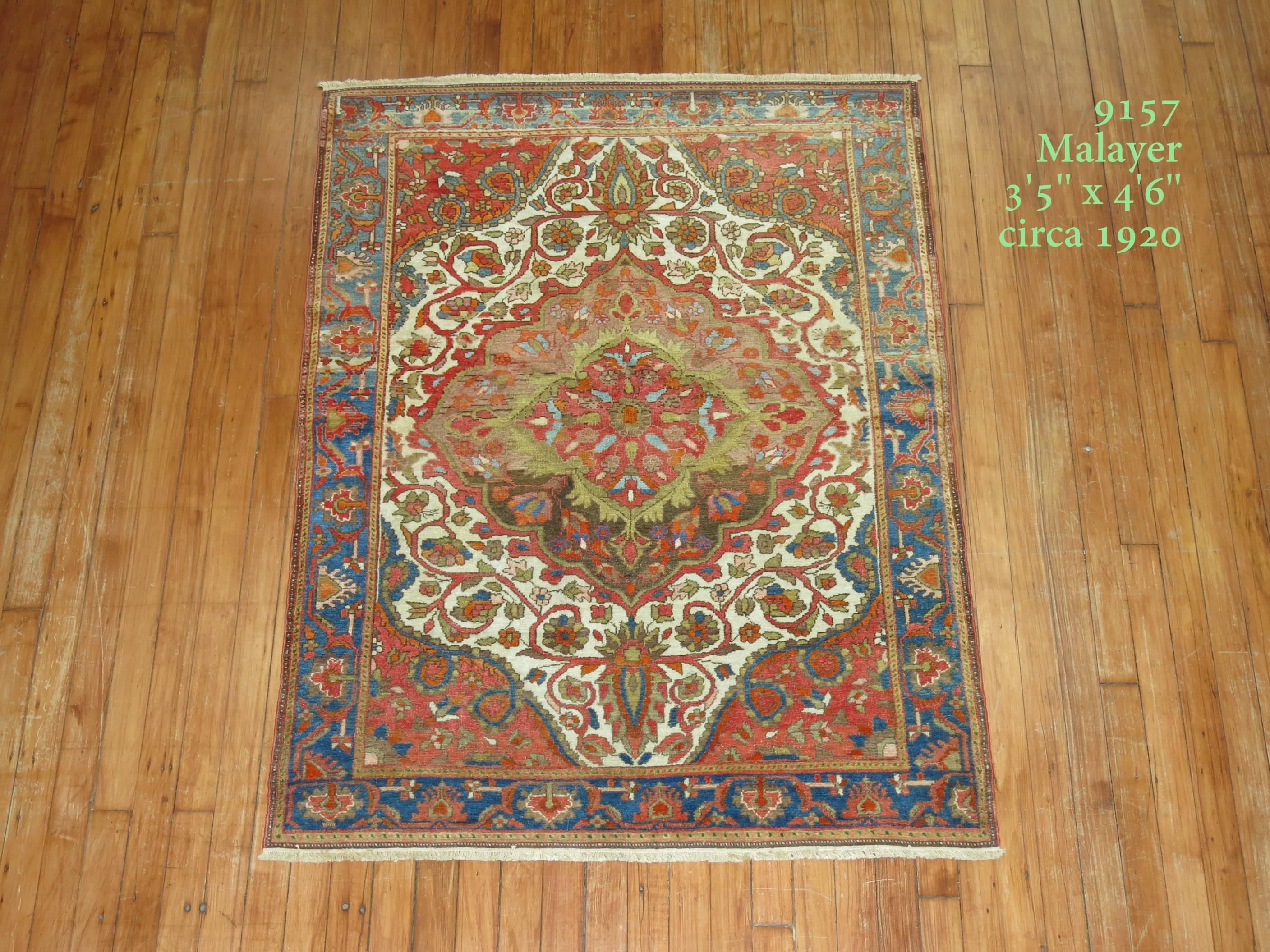 Un tapis persan Malayer coloré et de belle qualité, de niveau connaisseur. Fond ivoire avec médaillon de couleur marron doux, accents vert lime, coin orange rouille et bordure bleu ciel. Les tapis de cette qualité peuvent également servir de