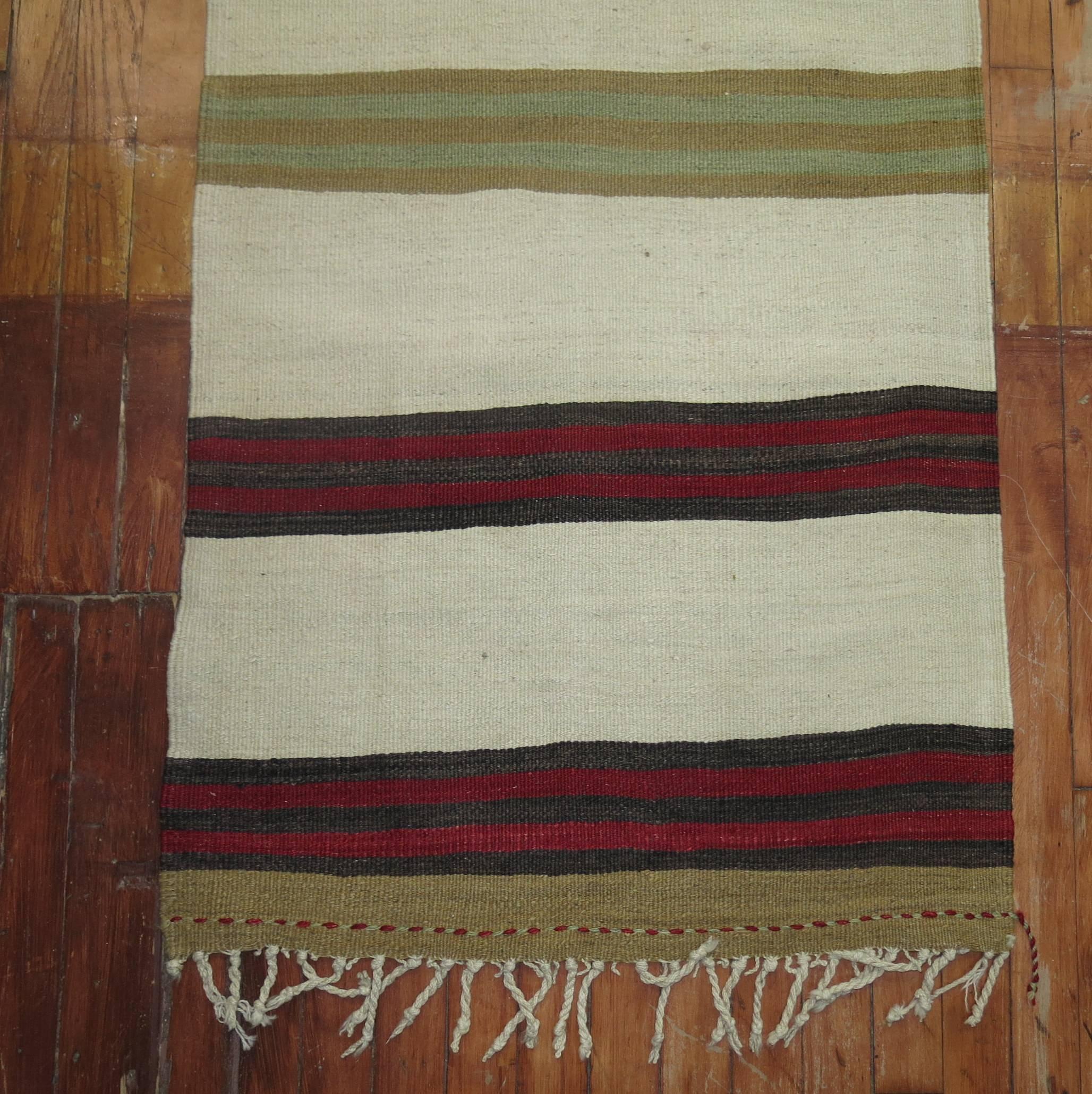 A mid-20th century narrow and long Turkish Kilim runner featuring an ivory colored ground,

circa mid-20th century, measures: 2'2