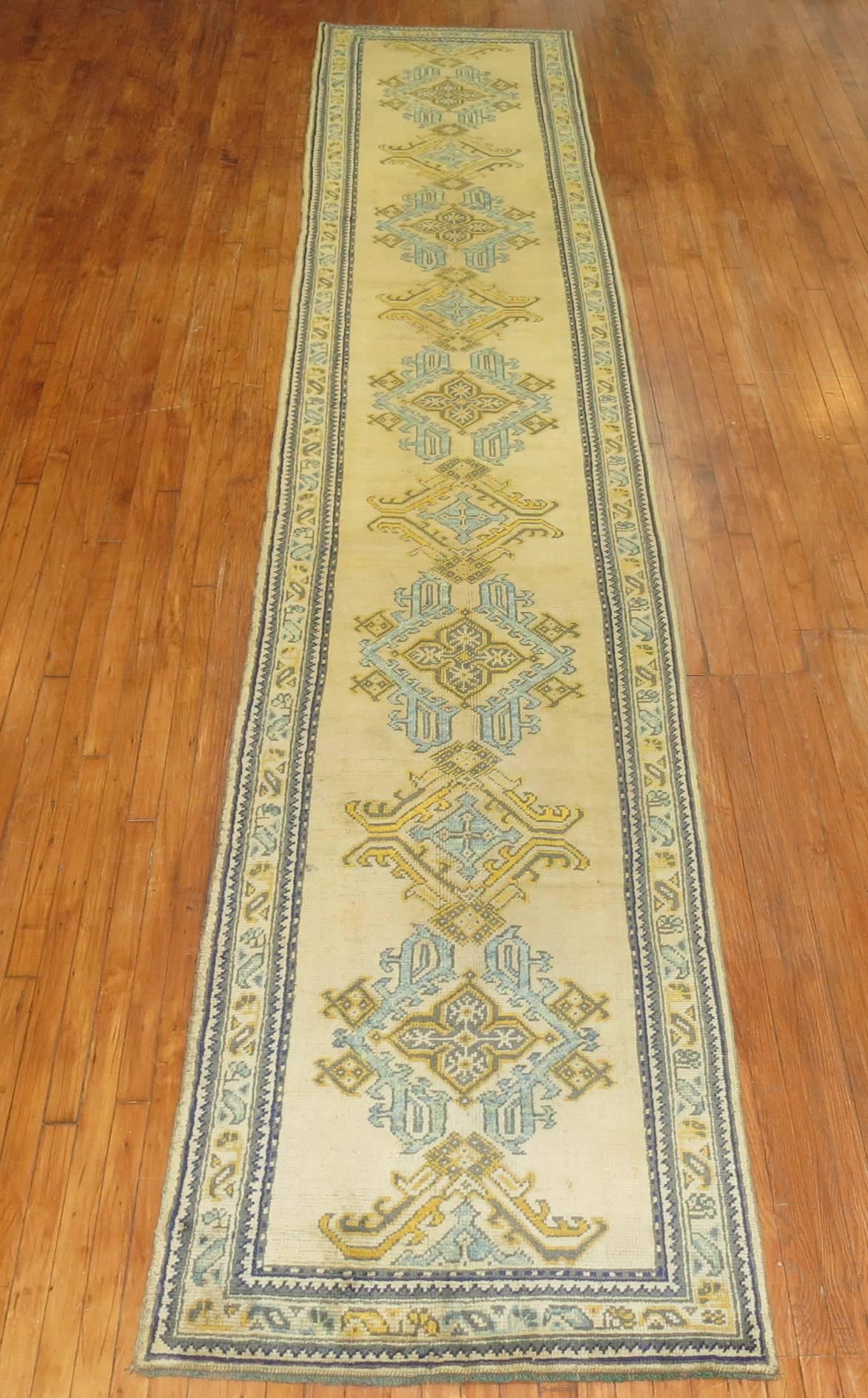 An authentic antique oushak runner. Accents in powder blue and mustard on a bone colored field and border.