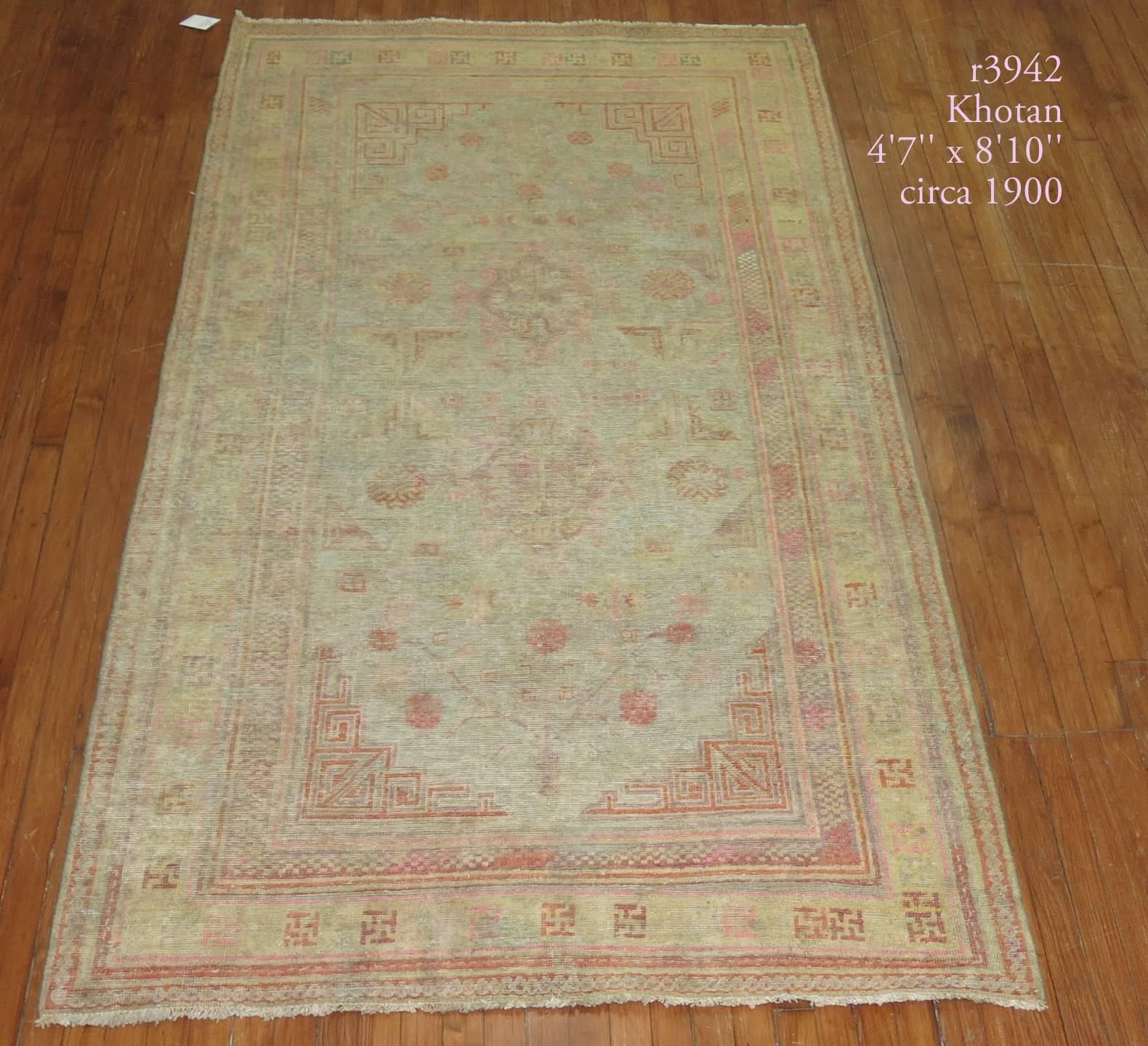 Late 19th century distressed antique Khotan rug featuring light accents in pink on a gray field.

Measures: 4'7
