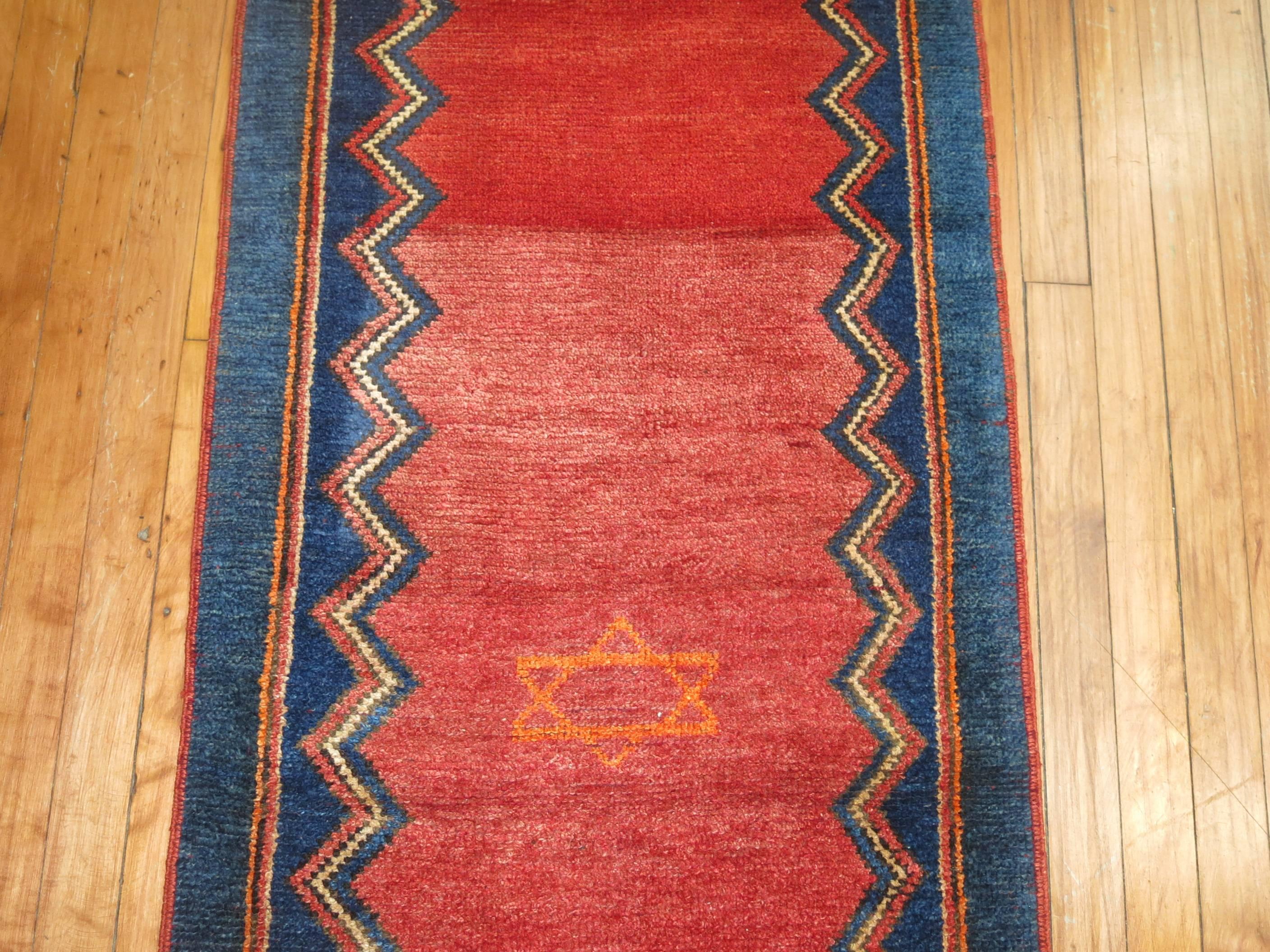 A vintage Turkish central Anatolian runner featuring four-star of David’s woven on a deep red/orange abrashed field and blue border.

2'2'' x 9'2''