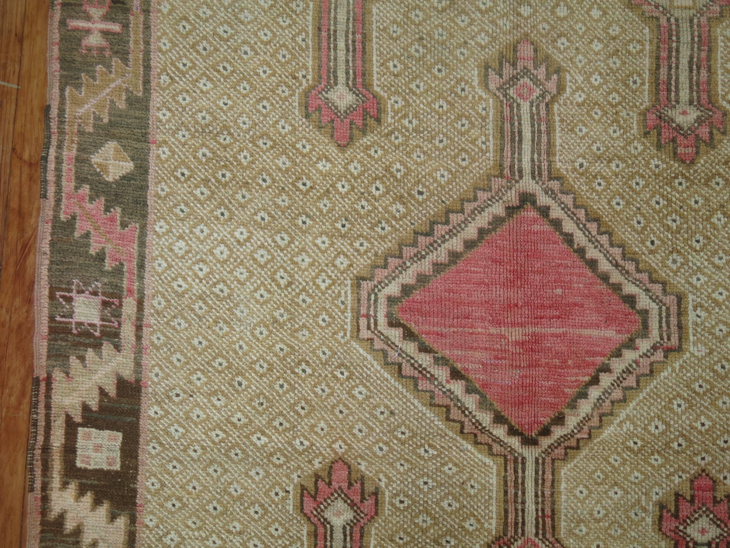 Quirky mid-20th century Turkish gallery rug. Pink and brown medallions on a khaki ground and brown border, circa 1940.

Size: 4'7” x 12'5”.