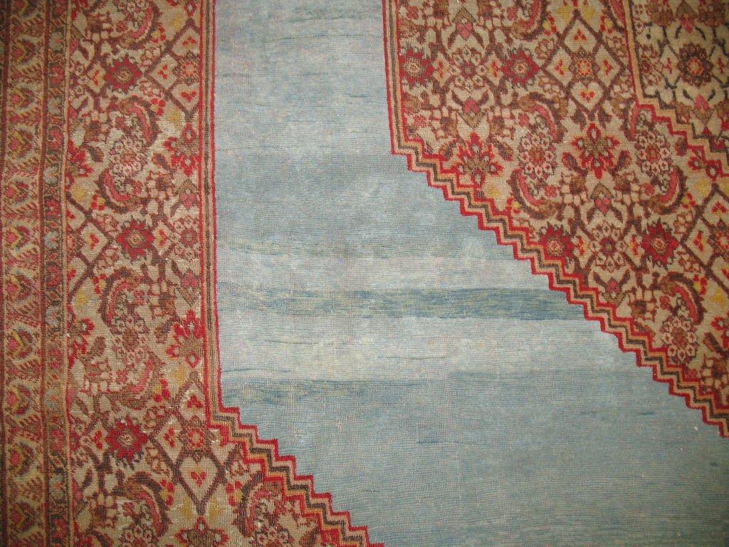 A gorgeous early 20th century antique open field Persian Tabriz rug with an illuminated electric blue background surrounded by an elegant cherry red border.