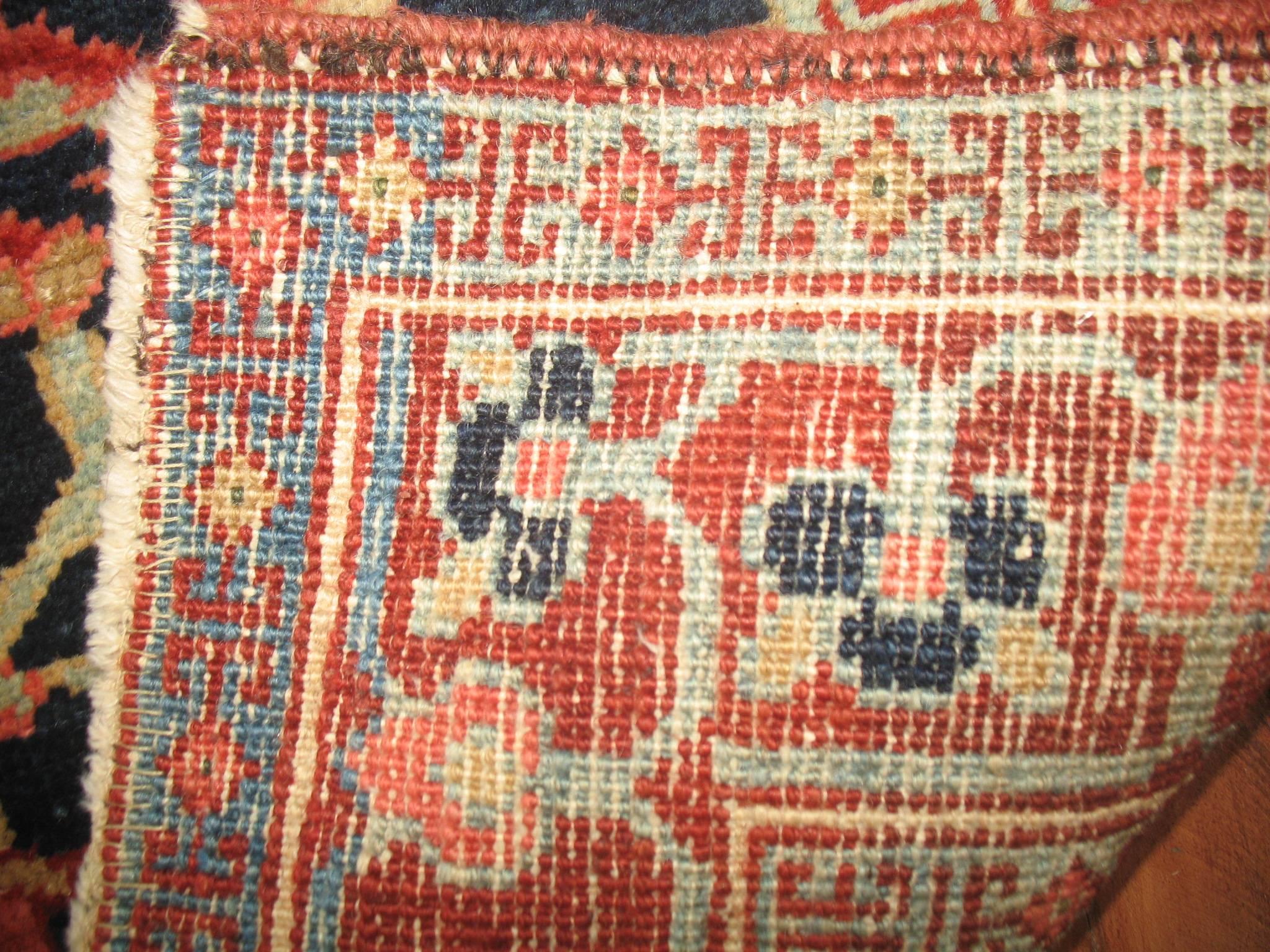 An early 20th century Persian Heriz throw rug with a classic medallion and border design in a tough to find small size for its type. Navy field and red border.